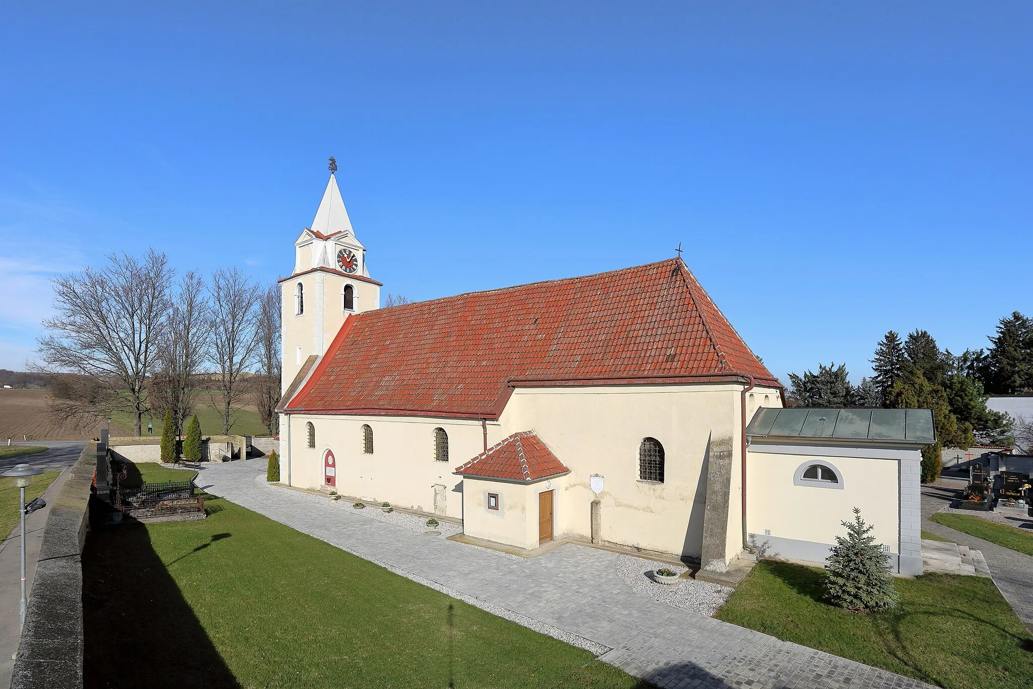 Photo showing: Südansicht der röm.-kath. Pfarrkirche hl. Georg in Wienerherberg, ein Ortsteil der niederösterreichischen Gemeinde Ebergassing. Eine gotische Wehrkirche aus dem 14./15. Jahrhundert, die teilweise von einer Bruchsteinmauer umgeben ist. Die Kirche ist innen barockisiert und 1727/28 wurde nordostseitig ein Seitenschiff angebaut. Südöstlich der Kirche, direkt an den Chor angebaut, befindet sich das 1804 errichtete Mausoleum für Johann Thomas von Trattner.