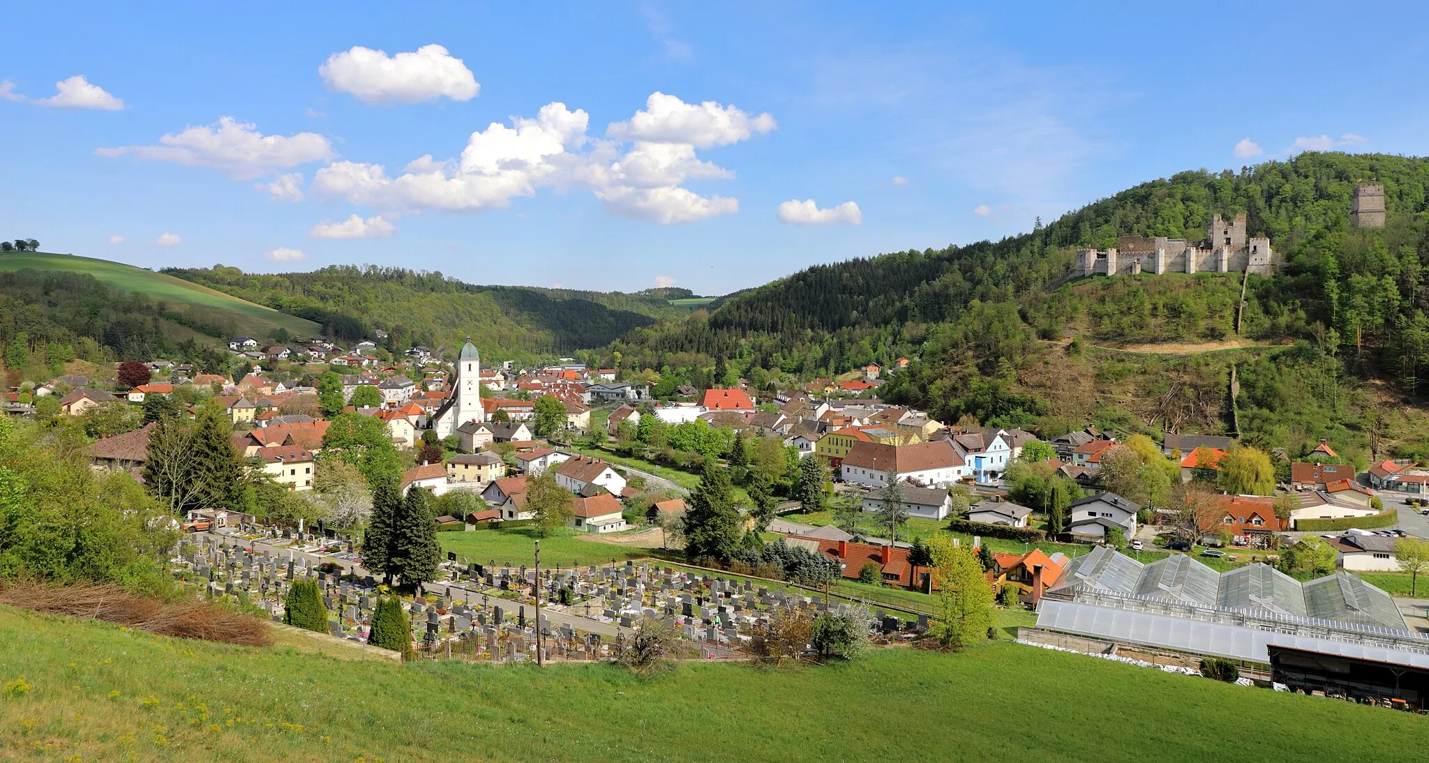 Photo showing: Nordwestansicht der niederösterreichischen Stadt Kirchschlag in der Buckligen Welt. Links im Vordergrund der Friedhof und dahinter die Pfarrkirche hl. Johannes der Täufer sowie rechts im Vordergrund die Gärtnerei Reisner und im Hintergrund die Burgruine Kirchschlag.