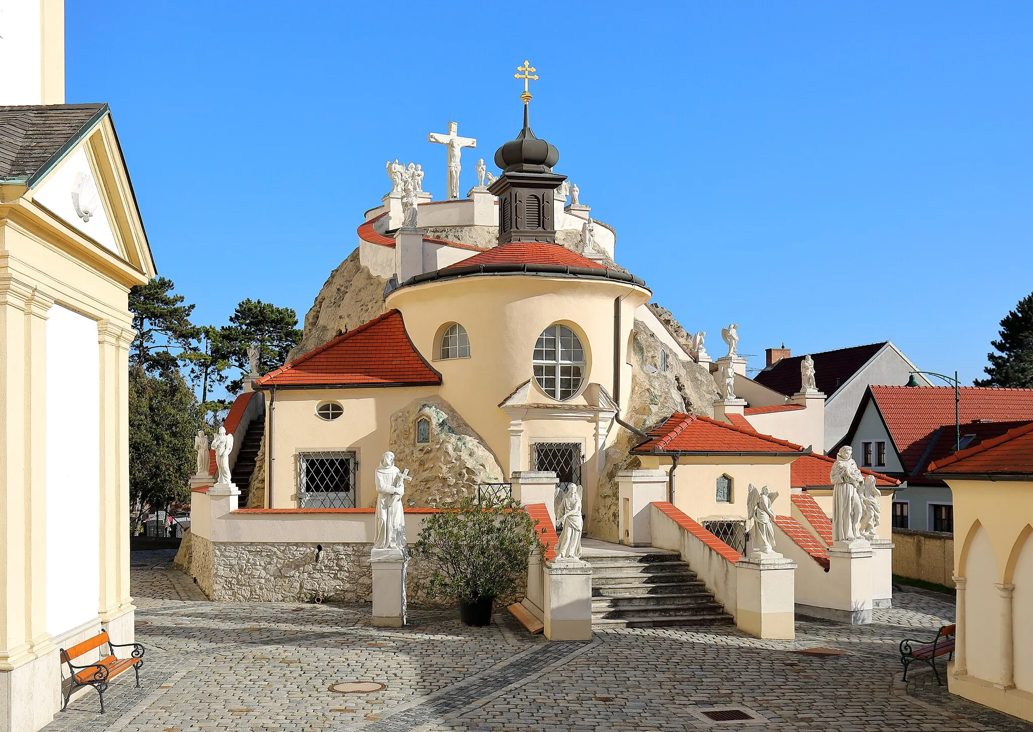 Photo showing: Westansicht des Kalvarienberges in der niederösterreichischen Gemeinde Maria-Lanzendorf sowie links ein Teil der Pfarr- und Wallfahrtskirche und rechts ein Teil der Heilig-Grab-Kapelle, die zum Kriegerdenkmal umgestaltet wurde. Errichtet wurde die leicht begehbare Anlage zur Darstellung der Leidensszenen Jesu durch den Franziskaner-Laienbruder Felix Niering und Helfern von 1699 bis 1701. Im Jahr 1709 wurde die Nachbildung der HI. Stiege, über die Christus zum Palast des Pilatus hinauf geführt worden war, hinzugefügt.