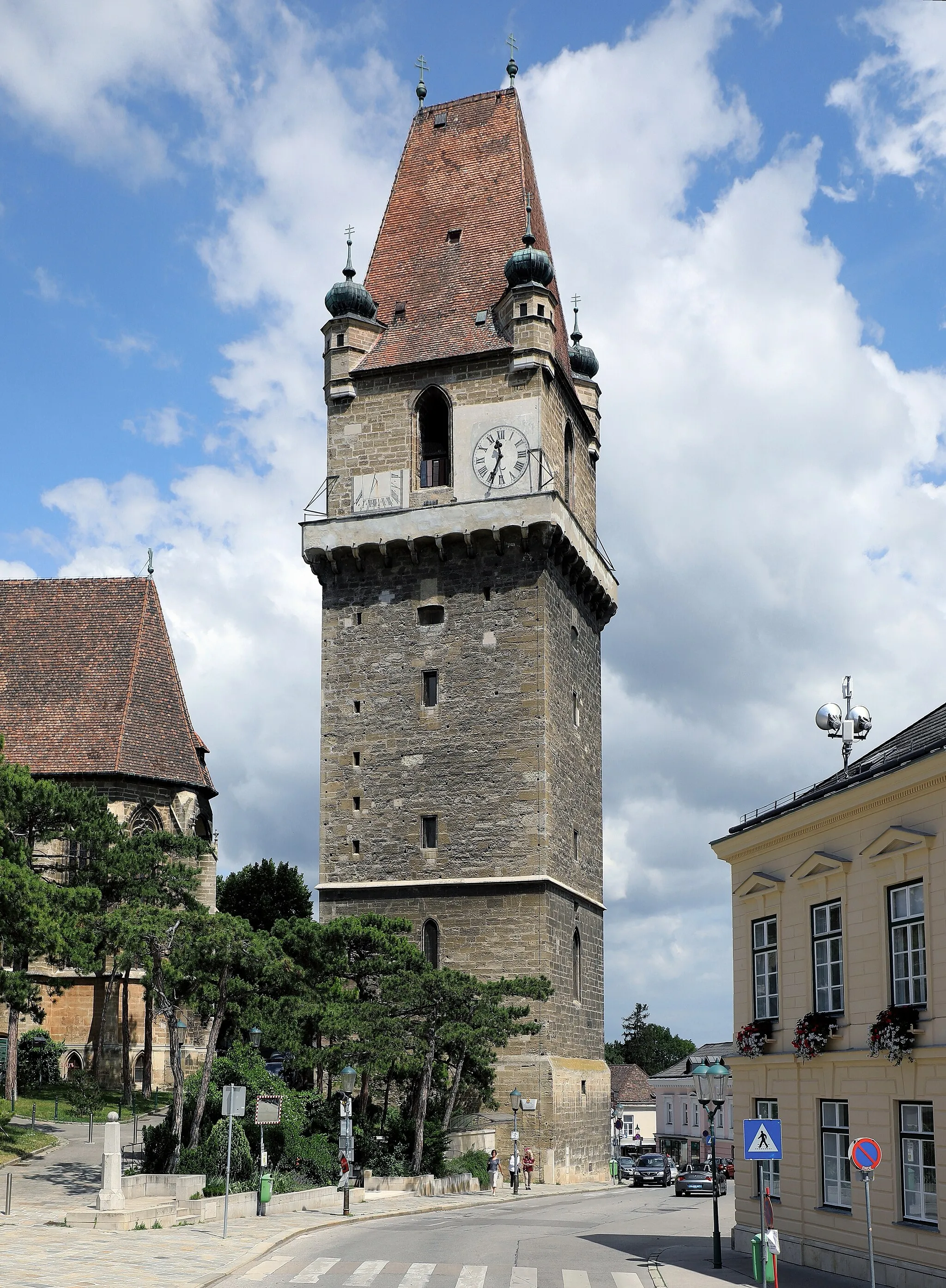 Photo showing: Der Wehrturm und markantes Wahrzeichen der niederösterreichischen Marktgemeinde Perchtoldsdorf. Links davon der Chor der Pfarrkirche hl. Augustinus und rechts das Gemeindeamt, ein ehemaliger späthistoristischer Meierhof aus dem Jahr 1838. Der Wehrturm wurde von 1450 bis 1521 errichtet. Er war ursprünglich ein Teil der ehemaligen Burgbefestigung und ostseitig in der Wehrmauer integriert.