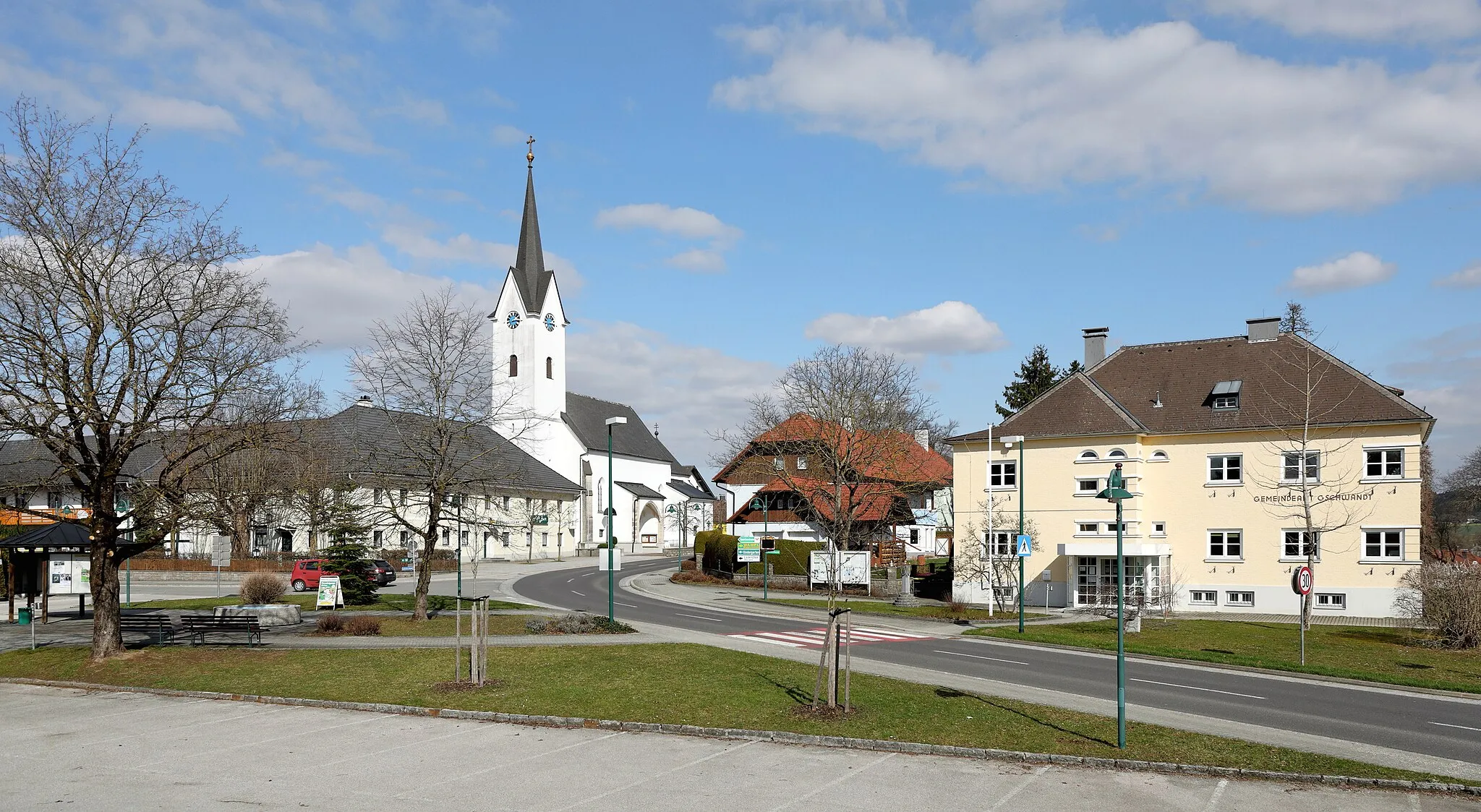 Photo showing: Südwestansicht des Ortszentrums der oberösterreichischen Gemeinde Gschwandt mit der röm.-kath. Pfarrkirche hl. Katharina und rechts dem Gemeindeamt.