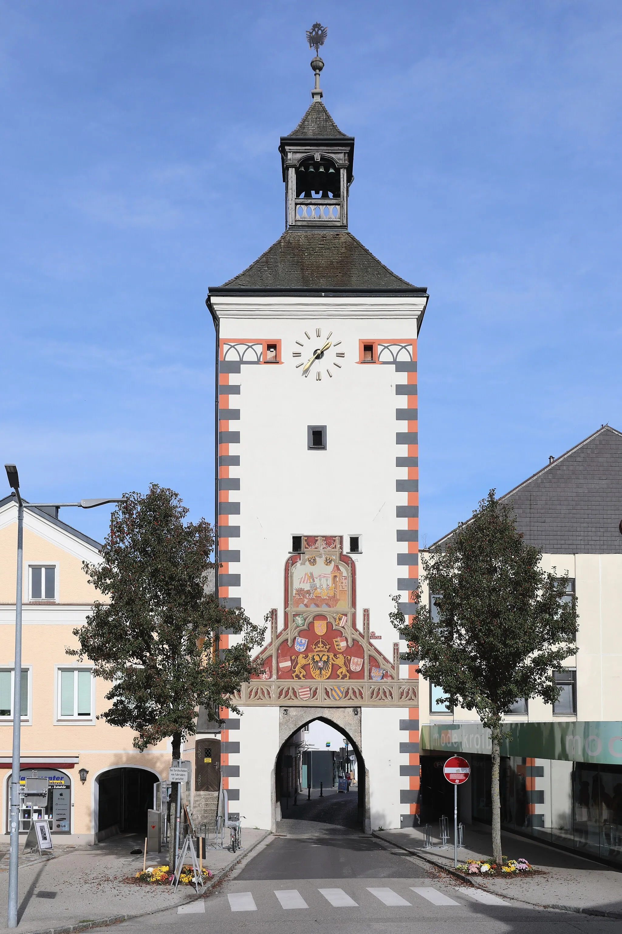 Photo showing: Südsüdwestansicht des oberen Stadtturmes der oberösterreichischen Stadt Vöcklabruck. Der obere Stadtturm entstand wie auch der untere Stadtturm zu Beginn des 14. Jahrhunderts. Der Turm hat eine gemauerte Höhe von fast 21 Meter und südwestseitig eine 1503 entstandenen Fassadenmalerei. Dessen Hauptmotiv zeigt die schon im ältesten bekannten Vöcklabrucker Stadtsiegel dargestellte Szene der beiden in die Stadt reitenden Ritter. Im dreieckigen Feld unterhalb sind die acht Wappen der österreichischen Erbländer dargestellt, sowie der von zwei Löwen gehaltene doppelköpfige Reichsadler und darüber das Stammwappen der Habsburger.