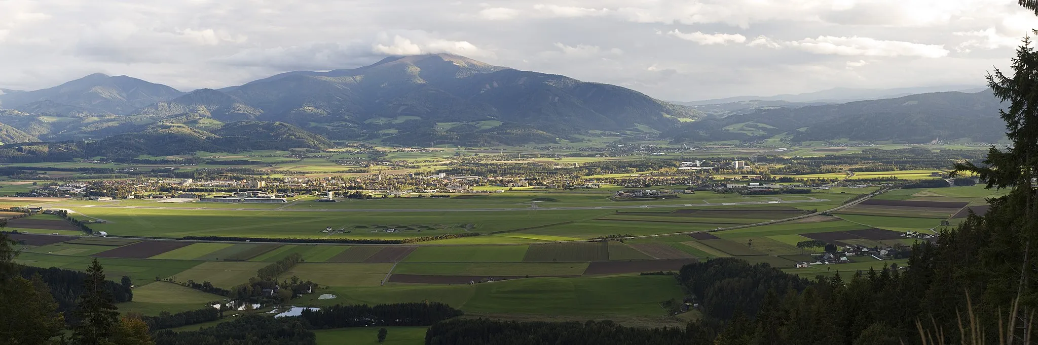 Photo showing: Blick auf Zeltweg und Umgebung von Norden. Im Vordergrund der Militärflughafen und die Murtalschnellstraße, im Hintergrund der Ameringkogel