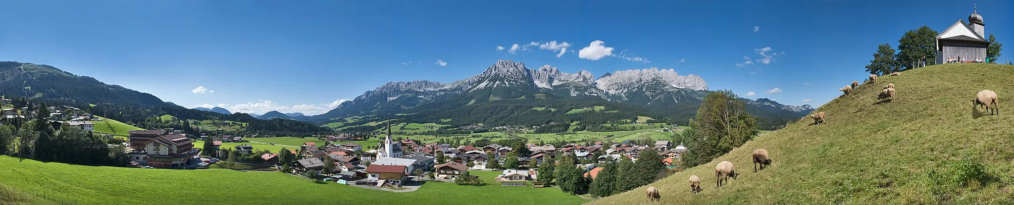 Photo showing: Panoramic view of Ellmau including the Visitation chapel to the right – a local landmark. The mountains behind the village belong to the Kaiser mountain range and are known as Wilder Kaiser (south face here).