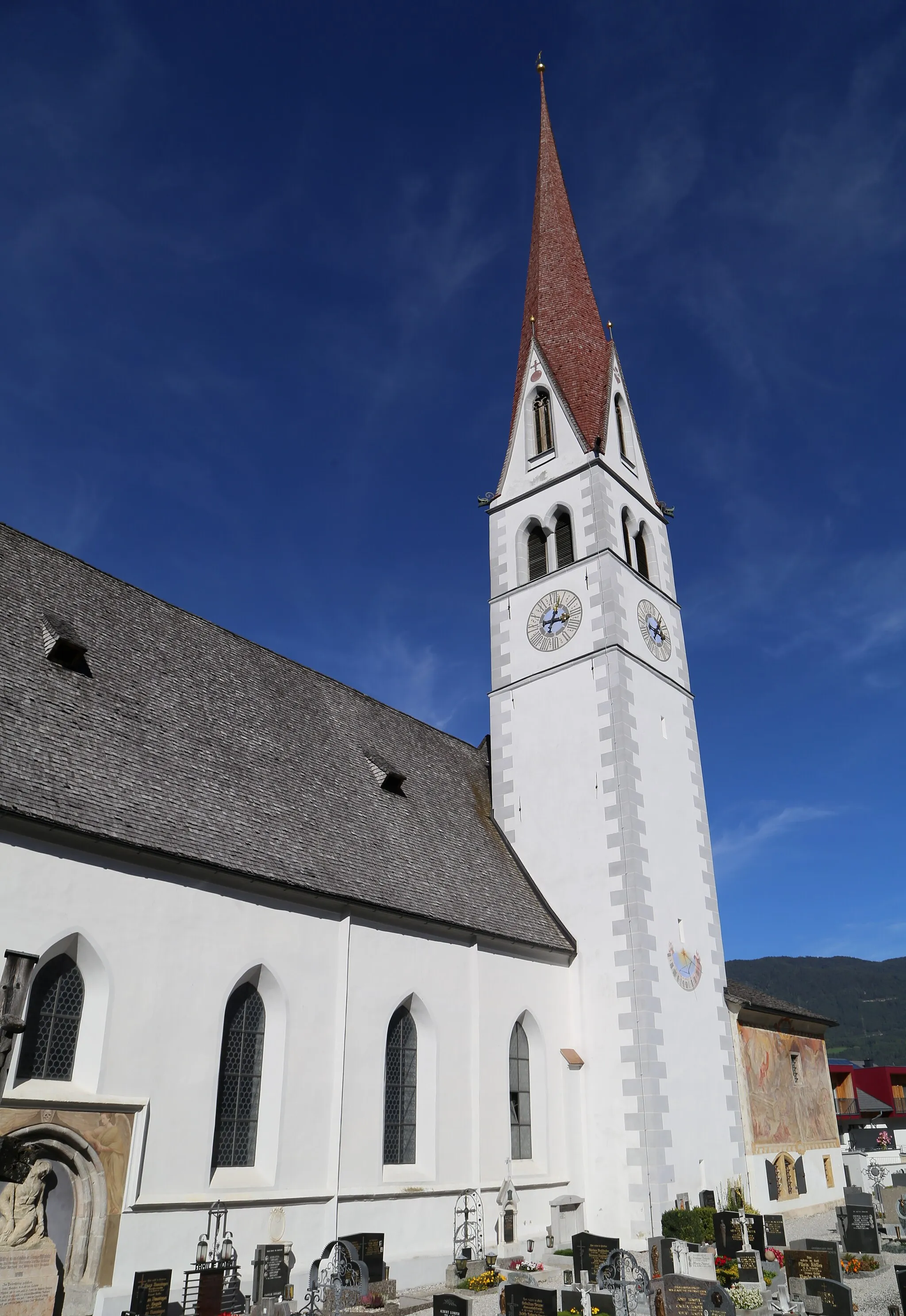 Photo showing: Kath. Pfarrkirche Mariä Himmelfahrt, Dorfplatz, Pfaffenhofen (Tirol); Über einer frühchristlichen Kirche wurde im 14./15. Jahrhundert ein spätgotischer Bau errichtet, der im 18. Jahrhundert barockisiert wurde. 1860/1863 wurde die Kirche nach Plänen von August Essenwein und Josef von Stadl erweitert und regotisiert. Der einschiffige Bau mit steilem Satteldach, zweijochigem Chor und dreiseitigem Chorschluss weist am Langhaus und Chor eine gotische Gliederung in Form von Dreikantlisenen und einem umlaufenden Kaffgesims auf. Die Westfassade zeigt einen steilen, im Ansatz abgetreppten Fassadengiebel und ein spitzbogig gekehltes Portal. An der Sakristei befindet sich ein Wandbild Auferstehung Christi und Jüngstes Gericht von Leopold Puellacher von 1826. Das Innere ist mit Pilastern gegliedert und weist im Langhaus eine durch Gurtbögen gegliederte Stichkappentonne, im Chor ein Sternrippengewölbe mit spätgotischer Wand- und Rankenmalerei auf