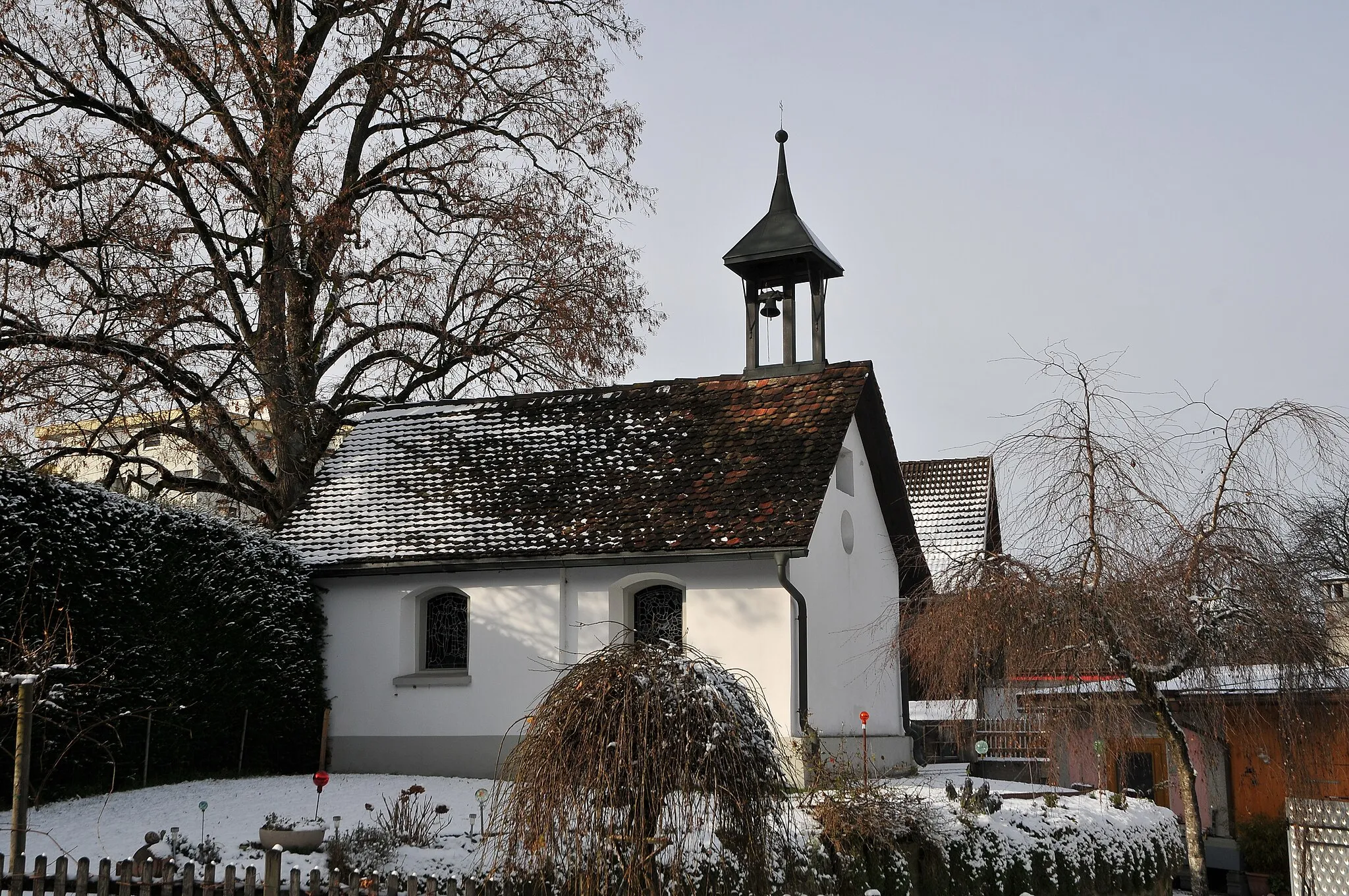 Photo showing: Die Kapelle hl. Wendelin in Einlis wird als Aufbahrungshalle verwendet. Sie wurde nach der Schlacht bei Frastanz erneuert. In einer Fassadennische ist eine Figur hl. Johann Nepomuk aus dem 18. Jahrhundert. Glasgemälde von Martin Häusle aus den Jahre 1963.