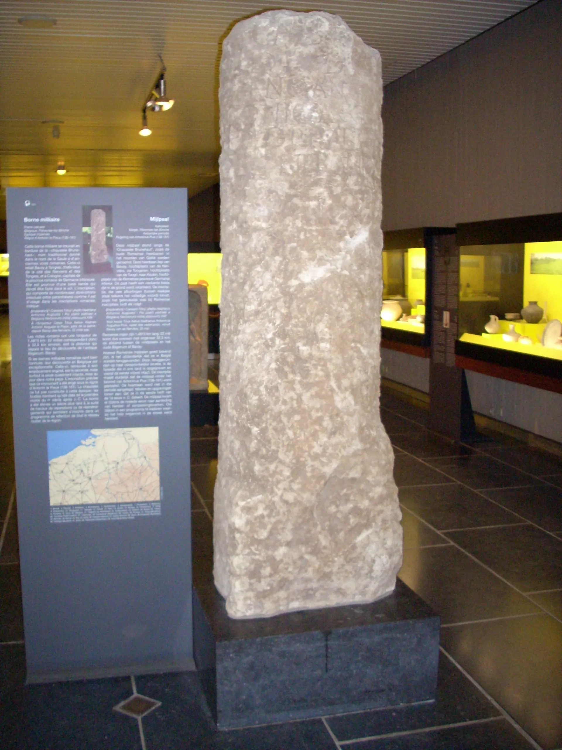 Photo showing: Borne de l'empire romain trouvé à Péronnes (près de Binche, Belgique) et exposée au musée de Mariemont. Transcription du panneau d'information : Borne milliaire
?
Belgique, ?
?
?
Cette borne milliaire se trouvait en bordure de la "chaussée Brunehaut", nom traditionnel donné dans le nord de la Gaule à d'anciennes voies romaines. Celle-ci reliait Bavay à Tongres, chef-lieux de la cité des Nerviens et des Tongris, et à Cologne, capitale de la province romaine de Germanie Inférieure. Elle est pourvue d'une base carrée qui (...) dans le sol. L'inscription qui comporte de nombreuses (...) comme il est d'usage dans les inscriptions romaines indique :

Les milles romains ont une longueur de 1,48xx km; 22 milles correspondaient donc à 32,5 km environ, soit la distance qui sépare le lien de découverte de l'antique (...), Bavay.
Si les bornes milliaires romaines sont bien connues, leur découverte en Belgique est exceptionnelle. Celle-ci retrouvées à son emplacement originel est la seconde mais surtout la (...) mis à jour pour notre pays. L'inscription précise que ce monument a été érigé sous le règne d'Antonin le Pieux (???-???). La chaussée ne fut pas construite à cette époque : les fouilles montrent qu'elle date de la première (...) après J-C. La borne a été (...) un siècle plus tard à la suite de travaux de réparation ou de réaménagement (...) dans le programme de (...) de tout sytème routier de la région.