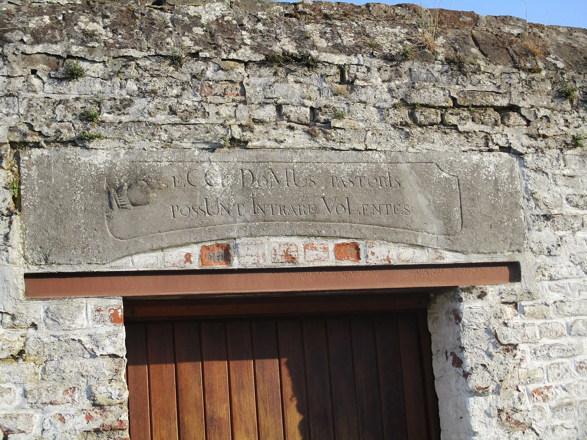 Photo showing: Steen boven ingang van pastorij van 1767 van Grand-Hallet (België) met tekst
"Ecce Domus pastoris possunt intrare volentis" (Hier kunt u het huis van de pastoor binnengaan)