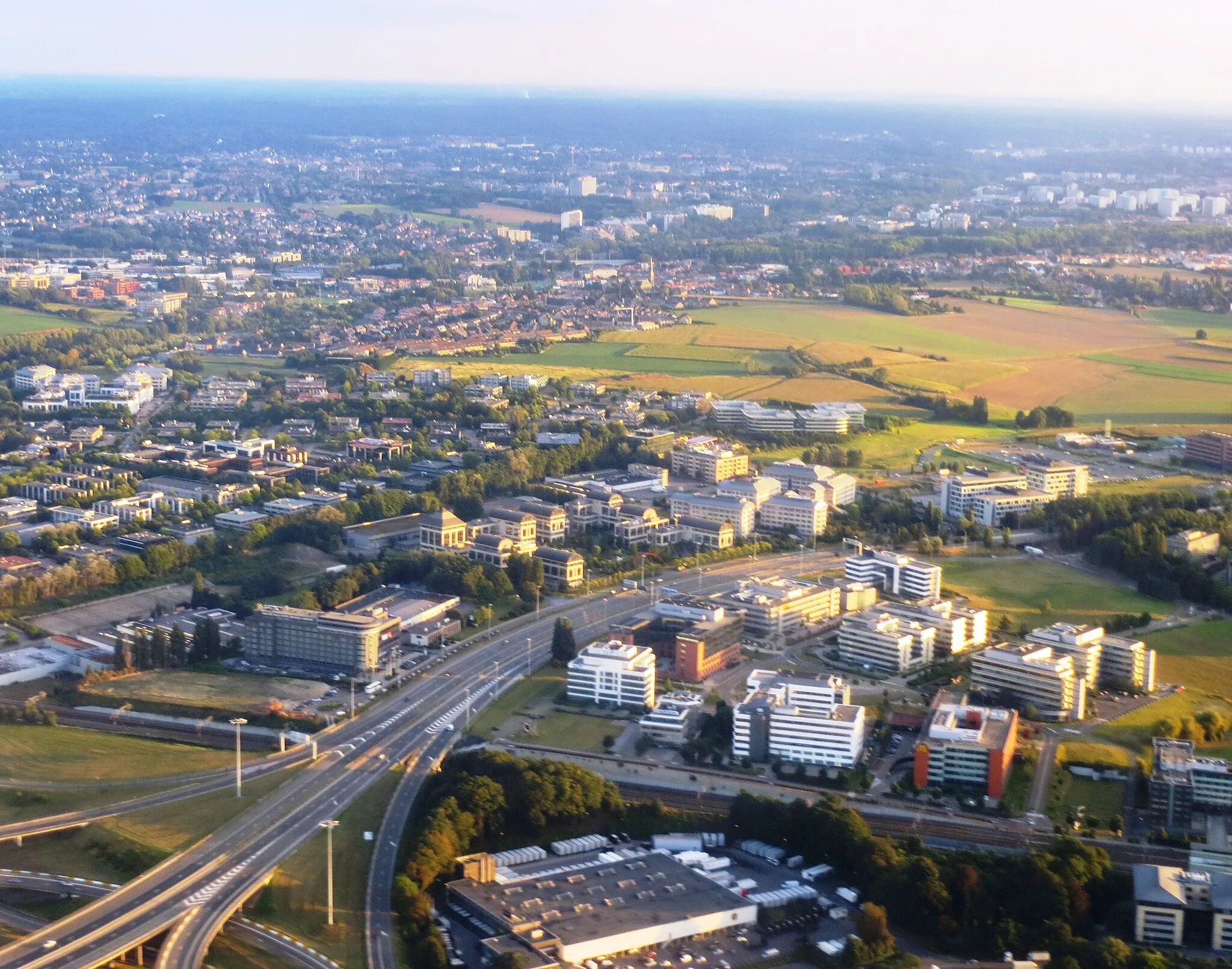 Photo showing: Aerial view over the Zaventeem area of northern Brussels, around the Brussels airport. Belgium. In the far lower end of the photo is DHL storagehouse, in the center right is the Cisco Systems campus of Belgium.