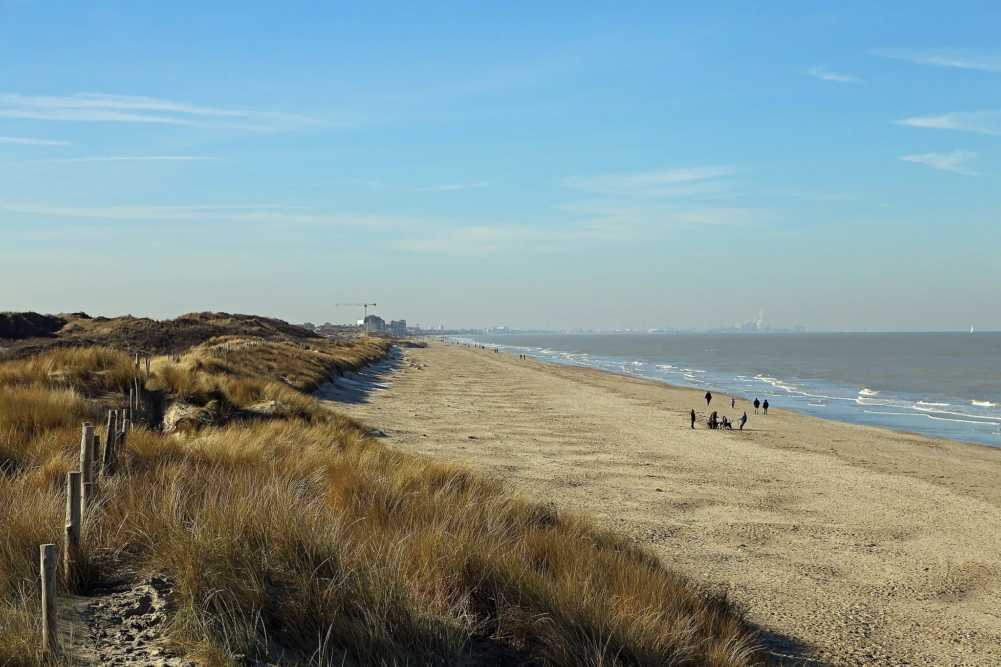 Photo showing: De Panne (Belgium): the beach on a bright winter's day, seen towards the French border. Far left: Bray-Dunes (France). Far right: the port of Dunkirk (France).