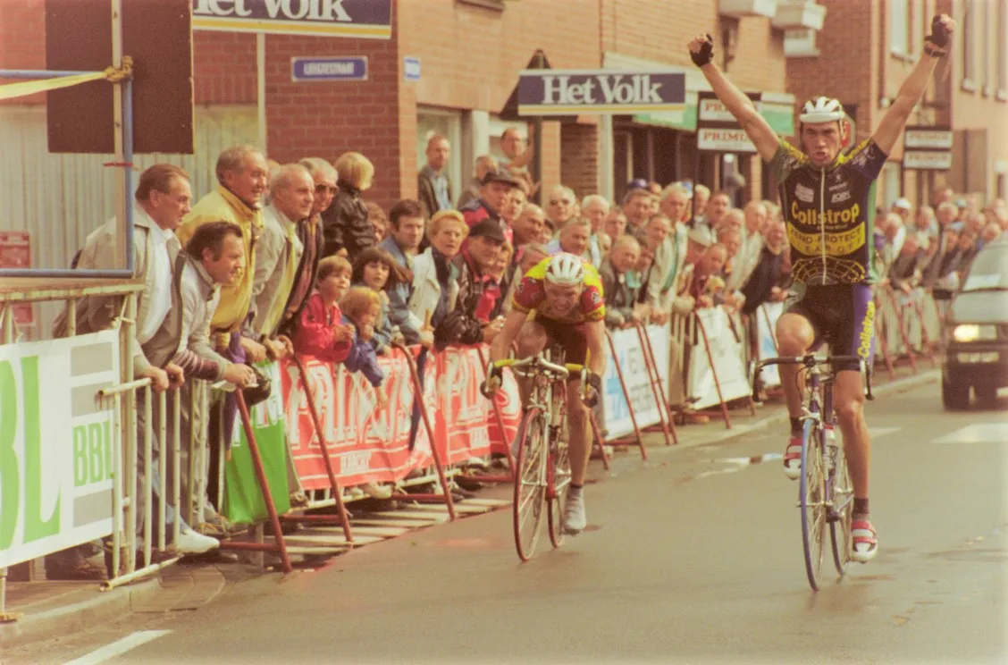 Photo showing: Danny Baeyens (Collstrop-Zeno-Protect-Clean Off) verslaat Franky De Buyst (Tönissteiner-Saxon) in de sprint tijdens de Sint-Elooisprijs in Ruddervoorde. Danny recht zich triomfantelijk en steekt zijn handen in de lucht. Lang de kant van de weg staan er toeschouwers die naar de renners kijken. De aankomst bevindt zich ter hoogte van de Torhoutsestraat. De wedstrijd werd verreden op 26 juni 1997.