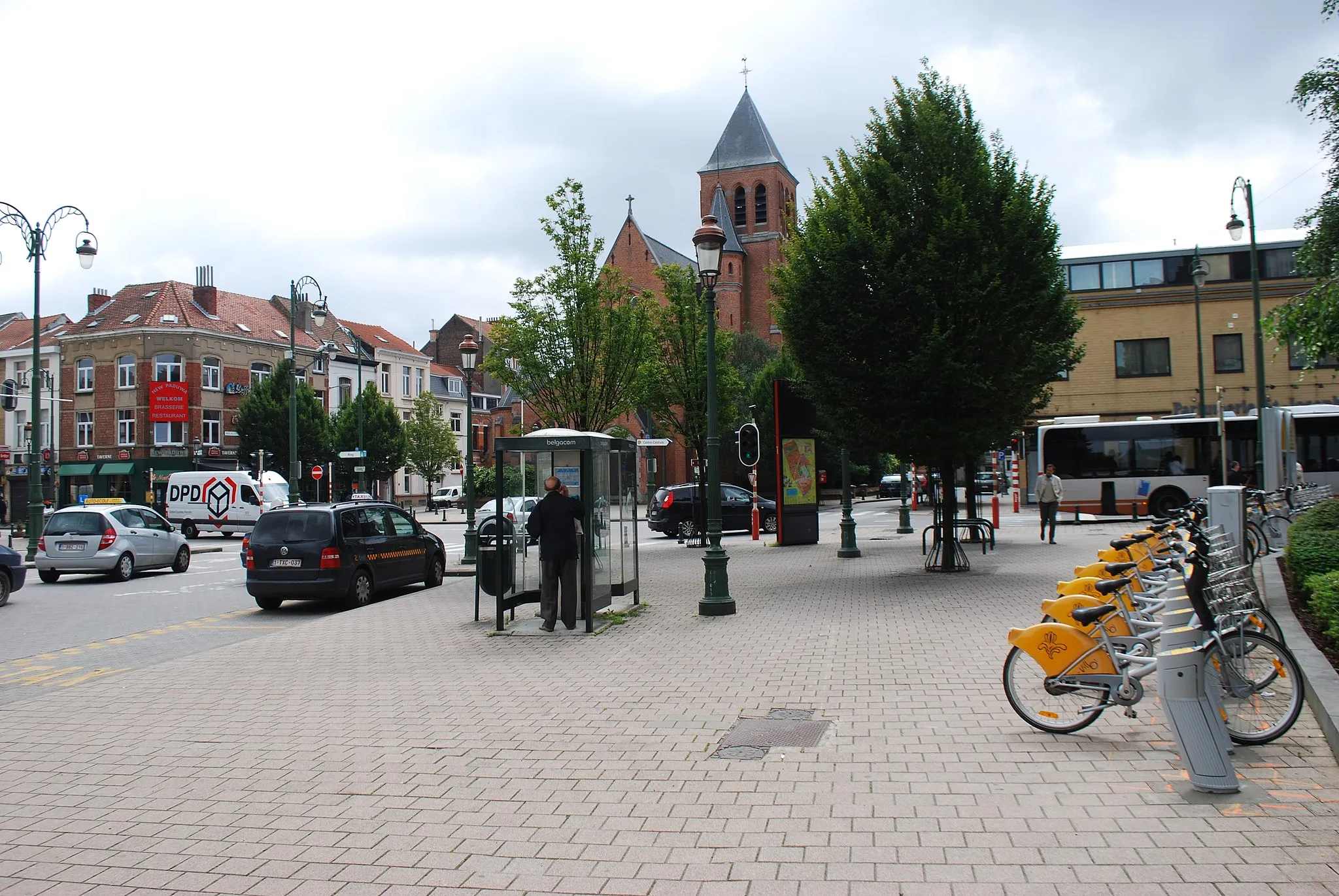 Photo showing: Vue de l'avenue des Anciens Combattants vers l'église Saint-Joseph à Evere (Bruxelles), la station de « vélos partagés », la station de taxis et les cabines téléphoniques
