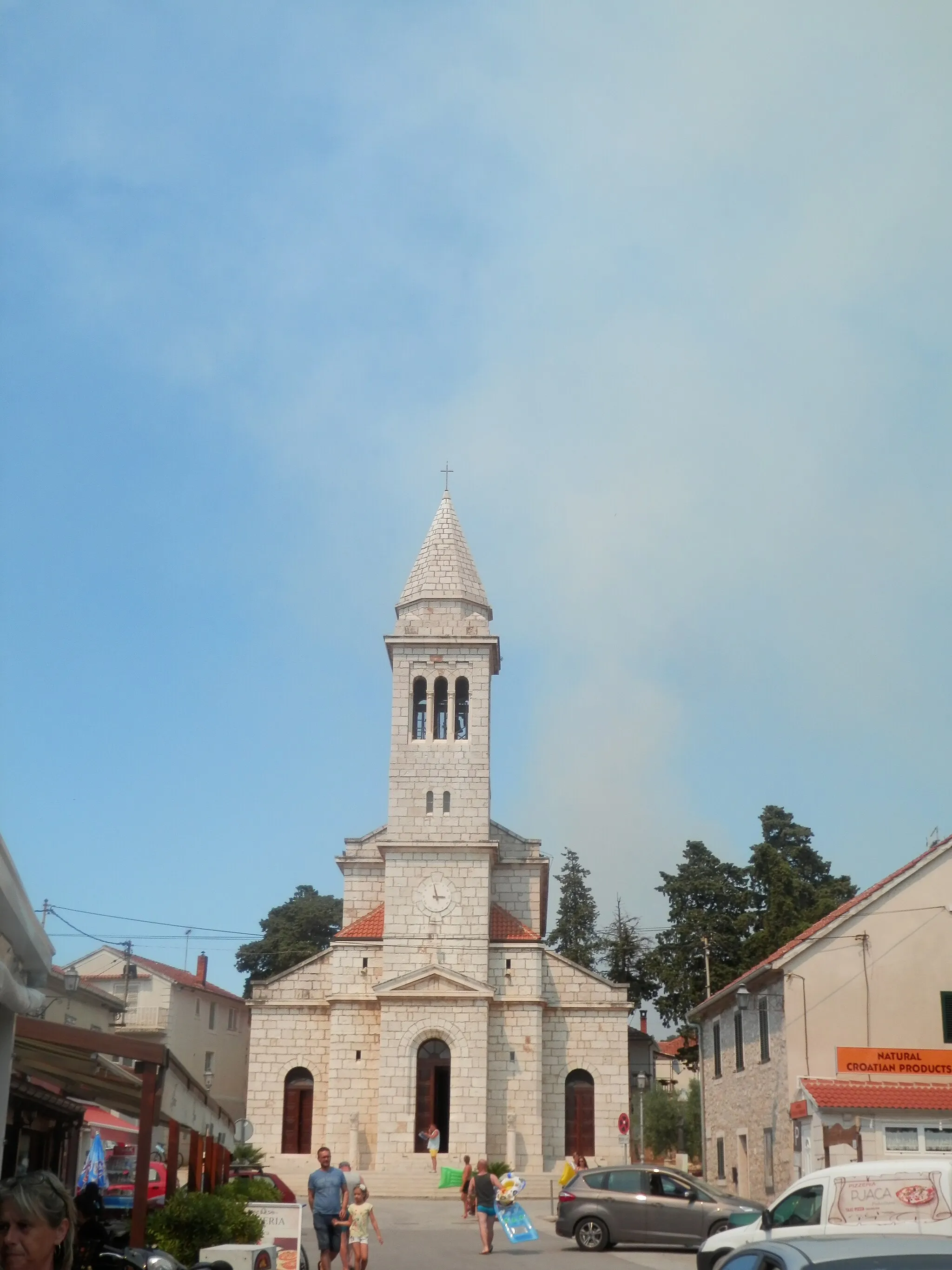 Photo showing: Kostol Nanebovstúpenia Pána, prímorské letovisko Pakoštane. Dalmácia, Chorvátsko.  Dym je z požiaru v obci Vrana.