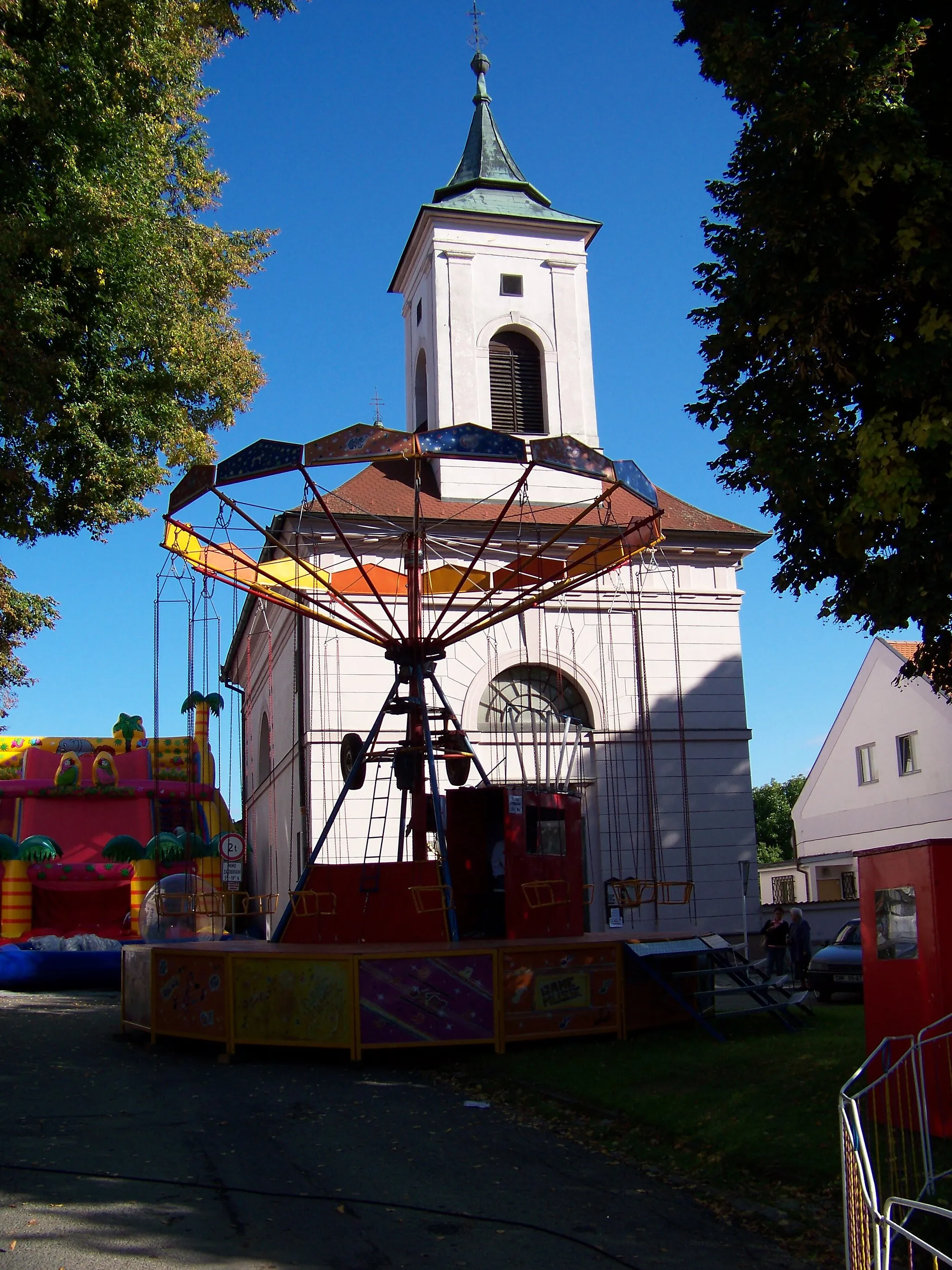 Photo showing: Sezimovo Ústí, Tábor District, South Bohemian Region, the Czech Republic. Hus Square, Church of the Exaltation of the Holy Cross and a swing carousel.