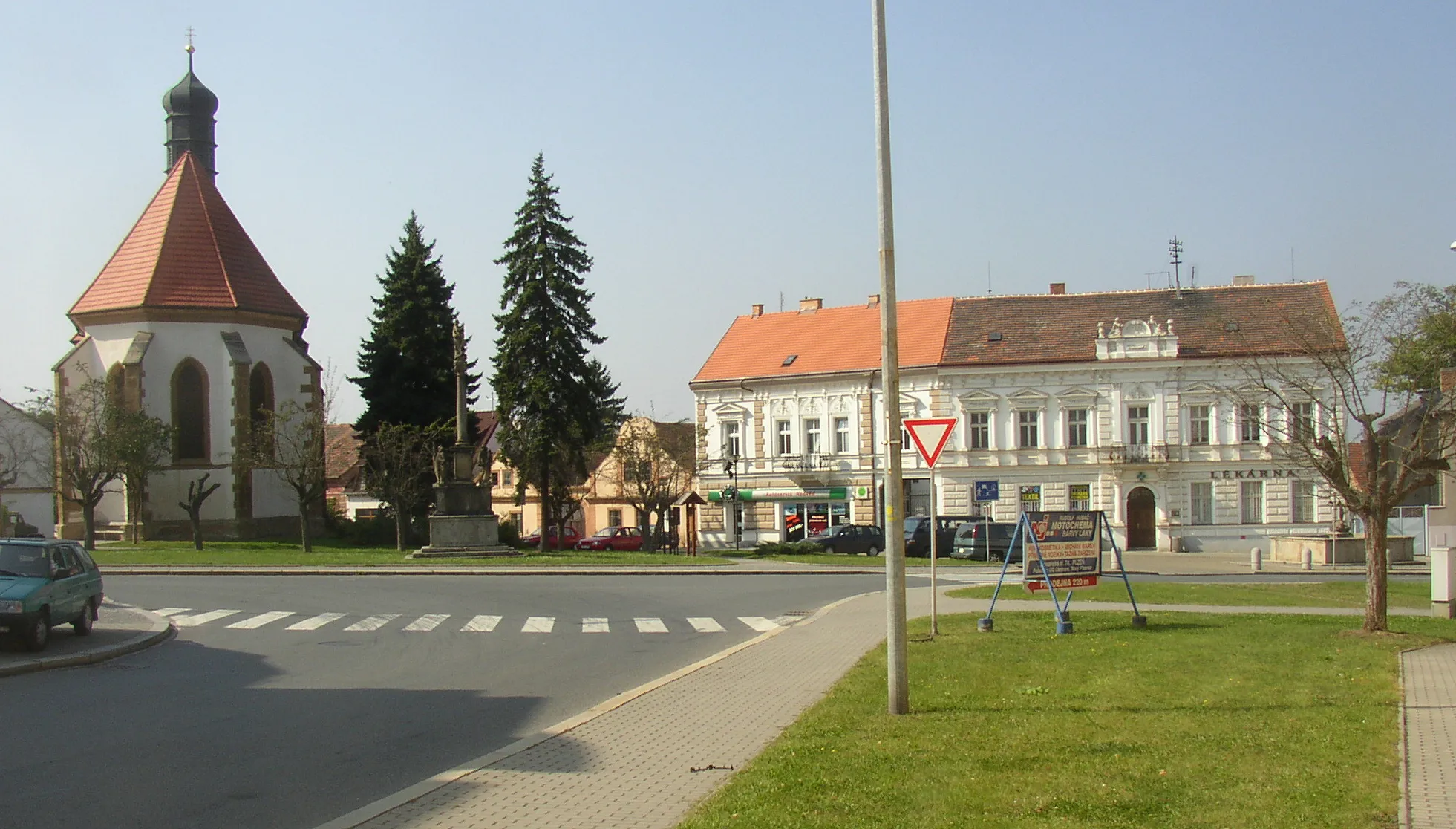 Photo showing: Masaryk Square in centre of Starý Plzenec, Plzeň-City District, Czech Republic. A view from the east. In the left Church of St John the Baptist, an edifice of Romanesque origin, later rebuilt in Gothic style, in the middle Marian Column from 1721 and on the very right edge a fountain with statue of Neptune from 1856.