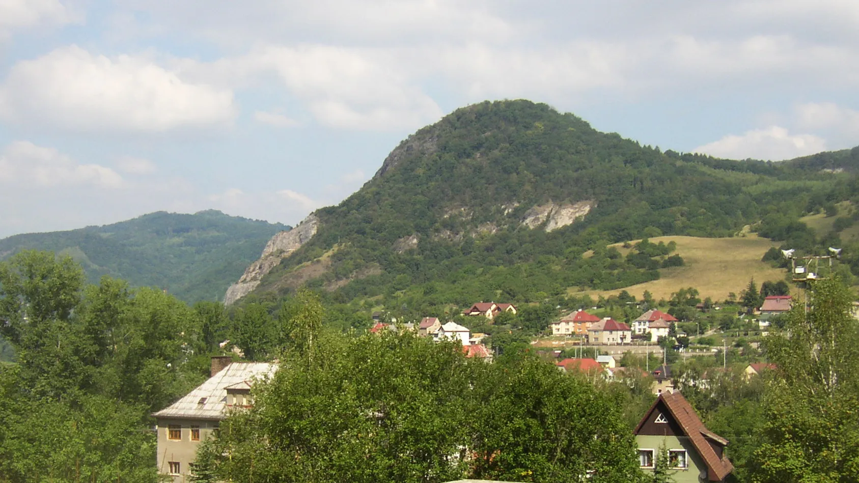 Photo showing: České středohoří, Czech Republic. Kozí vrch (Ziegenberg, 380 m) as seen from the southeast, over the Elbe from Velké Březno. Village of Neštědice (part of Povrly municipality) is located at the foothill. Left (western) hillside just above the house in the foreground still bears visible traces of an enormeous 18th century landslide.