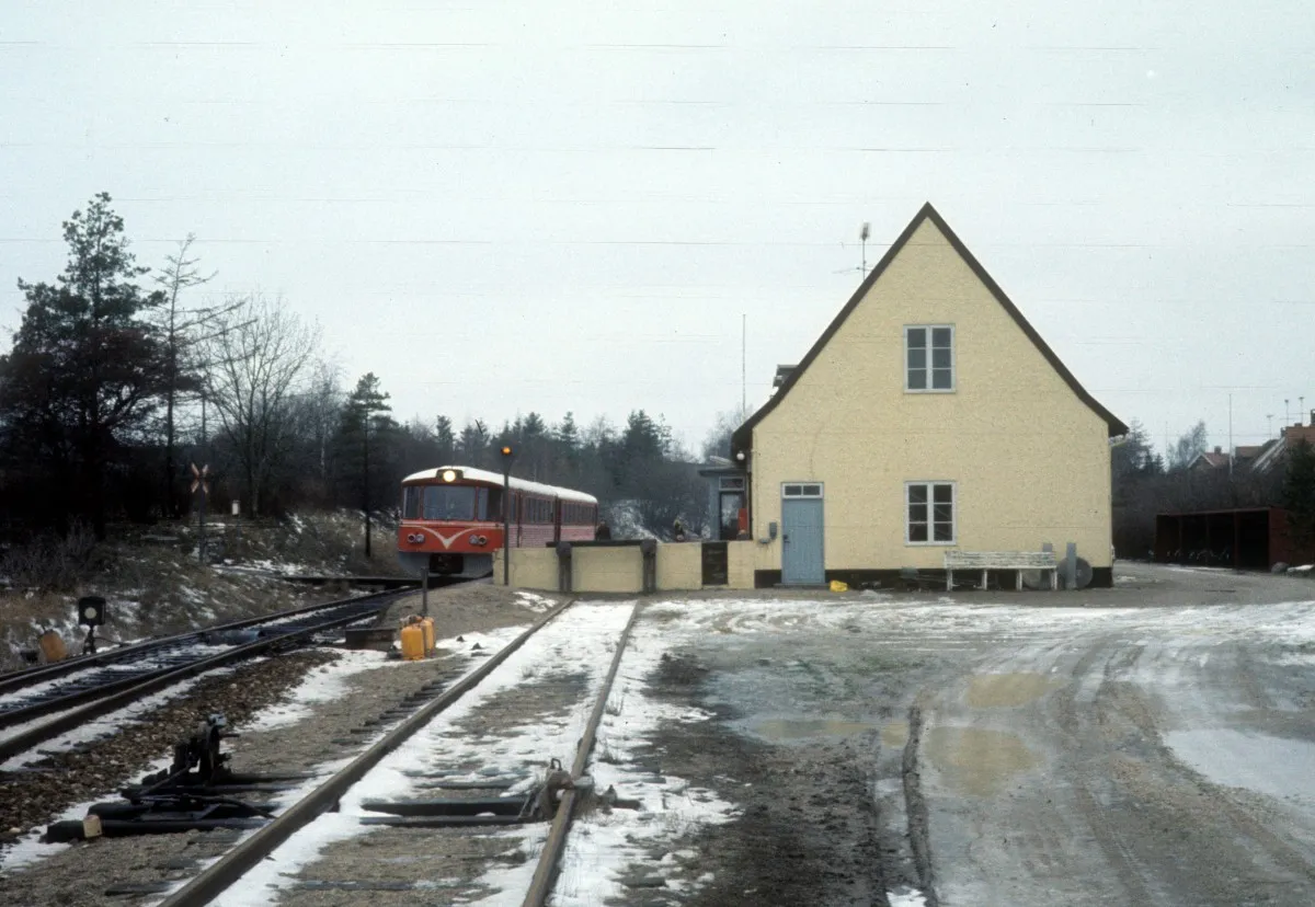 Photo showing: HFHJ (Hillerød-Frederiksværk-Hundested-Jernbane): Bahnhof Skævinge am 23. Dezember 1976. Am Bahnsteig hält ein Triebzug (Ym + Ys) in Richtung Hillerød.