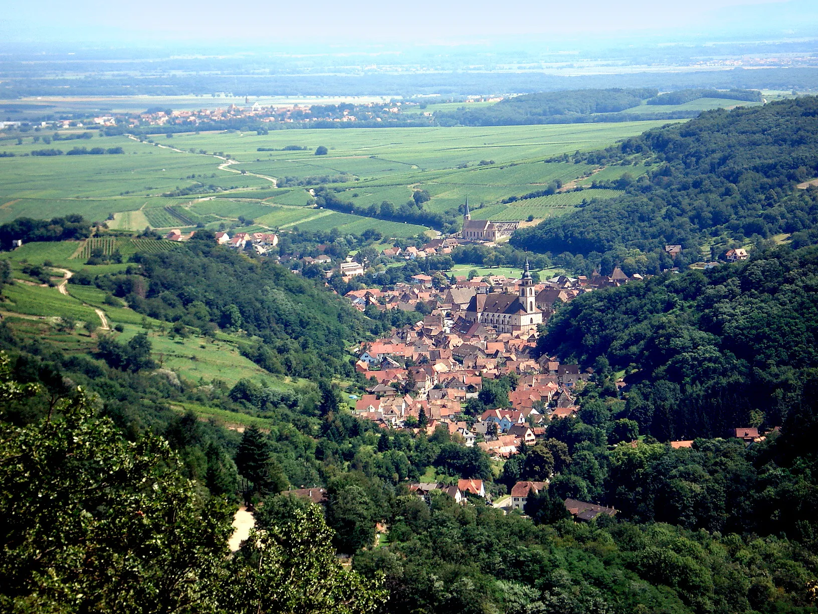 Photo showing: Le village d'Andlau (Bas-Rhin, Alsace, France), vu depuis le château du Spesbourg. On distingue l'église Saint-Pierre-et-Paul au milieu du village, et la chapelle Saint-André au-delà, un peu à l'écart. À l'arrière-plan : plaine d'Alsace, avec le village d'Epfig. Coup d'œil vers le sud-est.