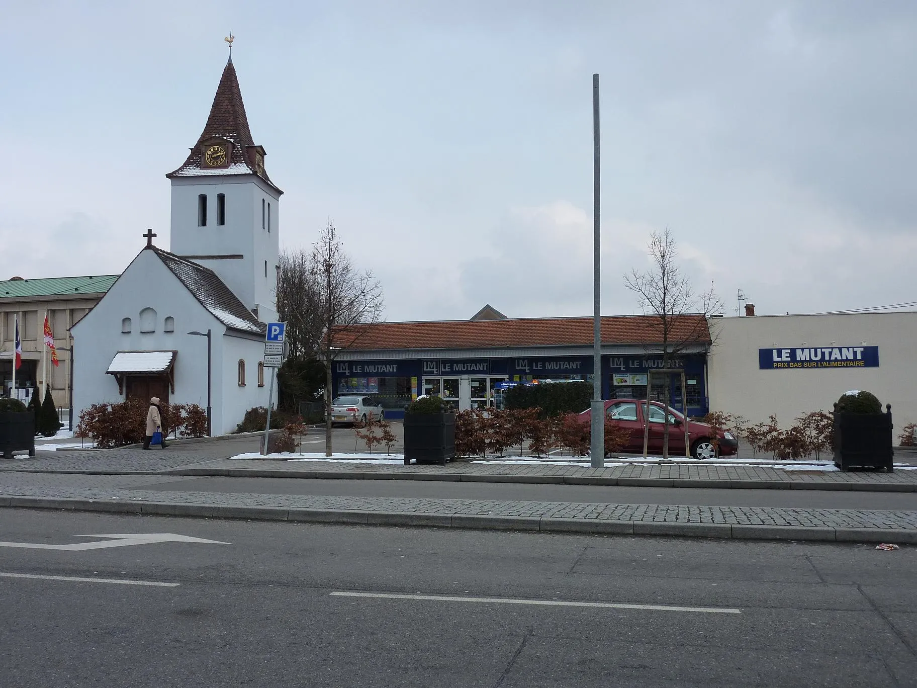 Photo showing: Le si beau centre de Hoenheim: à gauche de cette charmante chapelle la mairie, splendide horreur des 60s, et à sa droite un si beau supermarché... à signaler quand même qu'à sa rénovation on lui a rajouté ce si beau toit de tuiles....