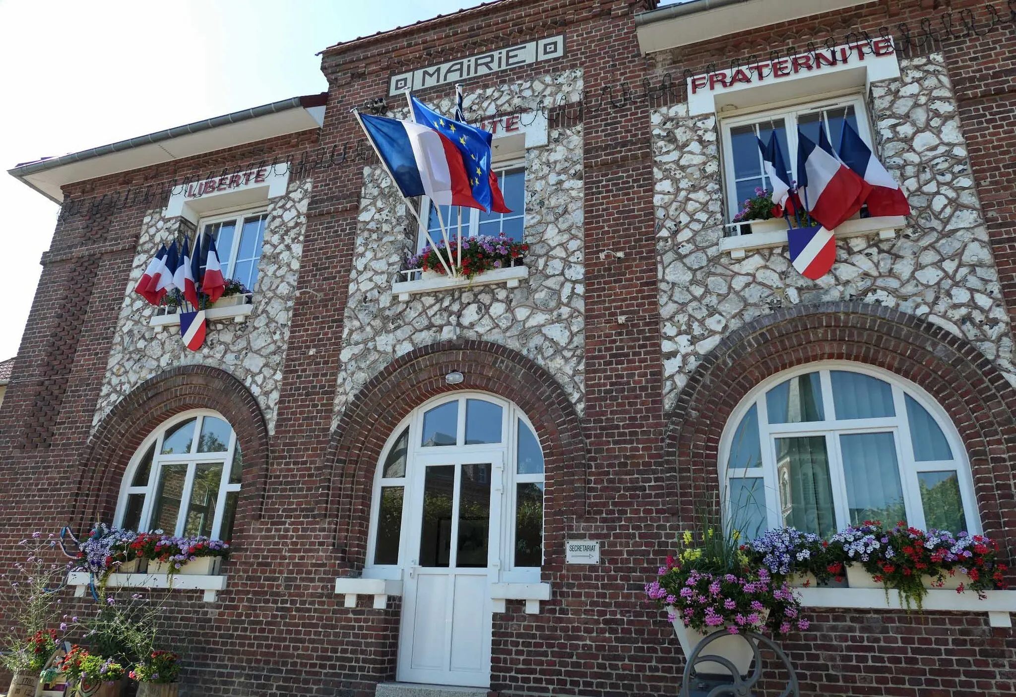 Photo showing: Bâtiment à étage en maçonnerie de pierre ornée de bandes en briques, ouvertures en plein cintre au rez de chaussée soulignées de brique.