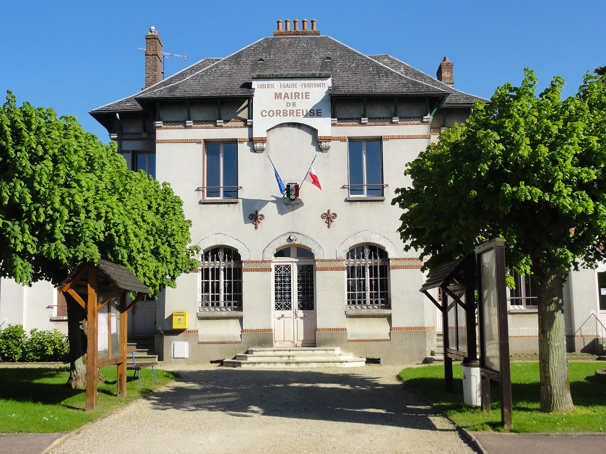 Photo showing: Mairie vue de face, drapeaux français et européen, ni voitures ni personnages. Ciel bleu de printemps.