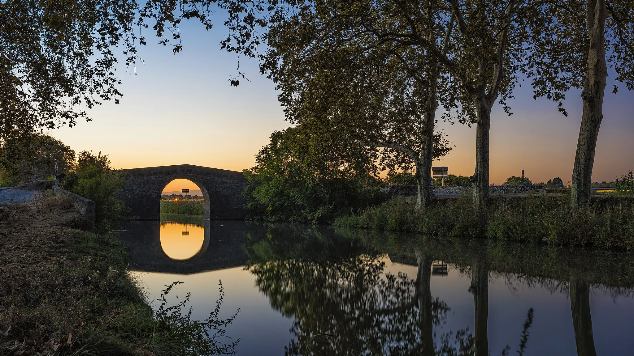 Photo showing: The Caylus Bridge reflected in the Canal du Midi. Villeneuve-lès-Béziers - Hérault, France
