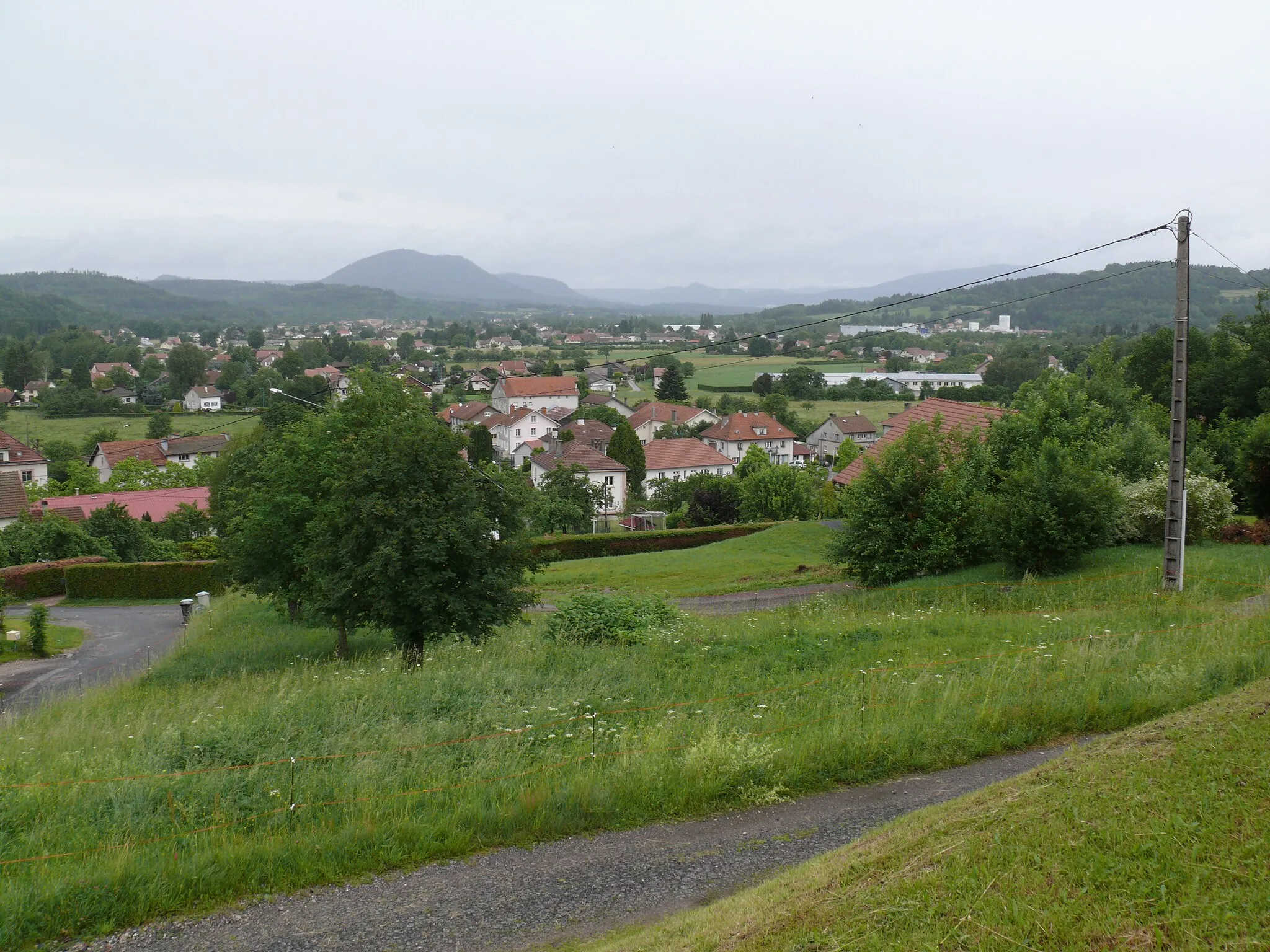 Photo showing: Anould (Vosges, France) on a rainy day, seen from the stairs of the église Saint-Antoine (Saint Anthony church). In the background the valley of the Meurthe, looking in direction of Saint-Dié (not visible), and at the left the Kemberg.