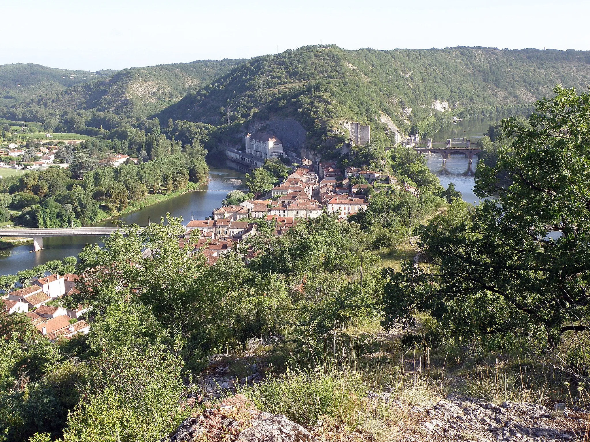 Photo showing: Luzech, ville dans le département du Lot, région Midi-Pyrénées, France.
Vue générale de la ville prise depuis le sommet de la montagne de la Pistoule (alt. 189m), située au sud de la ville, et dont on voit les pentes à l'avant-plan. Coup d’œil vers le nord. On aperçoit : la ville de Luzech sur les bords du Lot, occupant l'isthme du cingle (=méandre) de Luzech ; la centrale électrique, au fond, au centre gauche, sur la rive du Lot ; le donjon, au fond, au centre droit, perché sur le rocher de Saint-Projet; derrière le donjon, montagne de l'Impernal (alt. 247m).