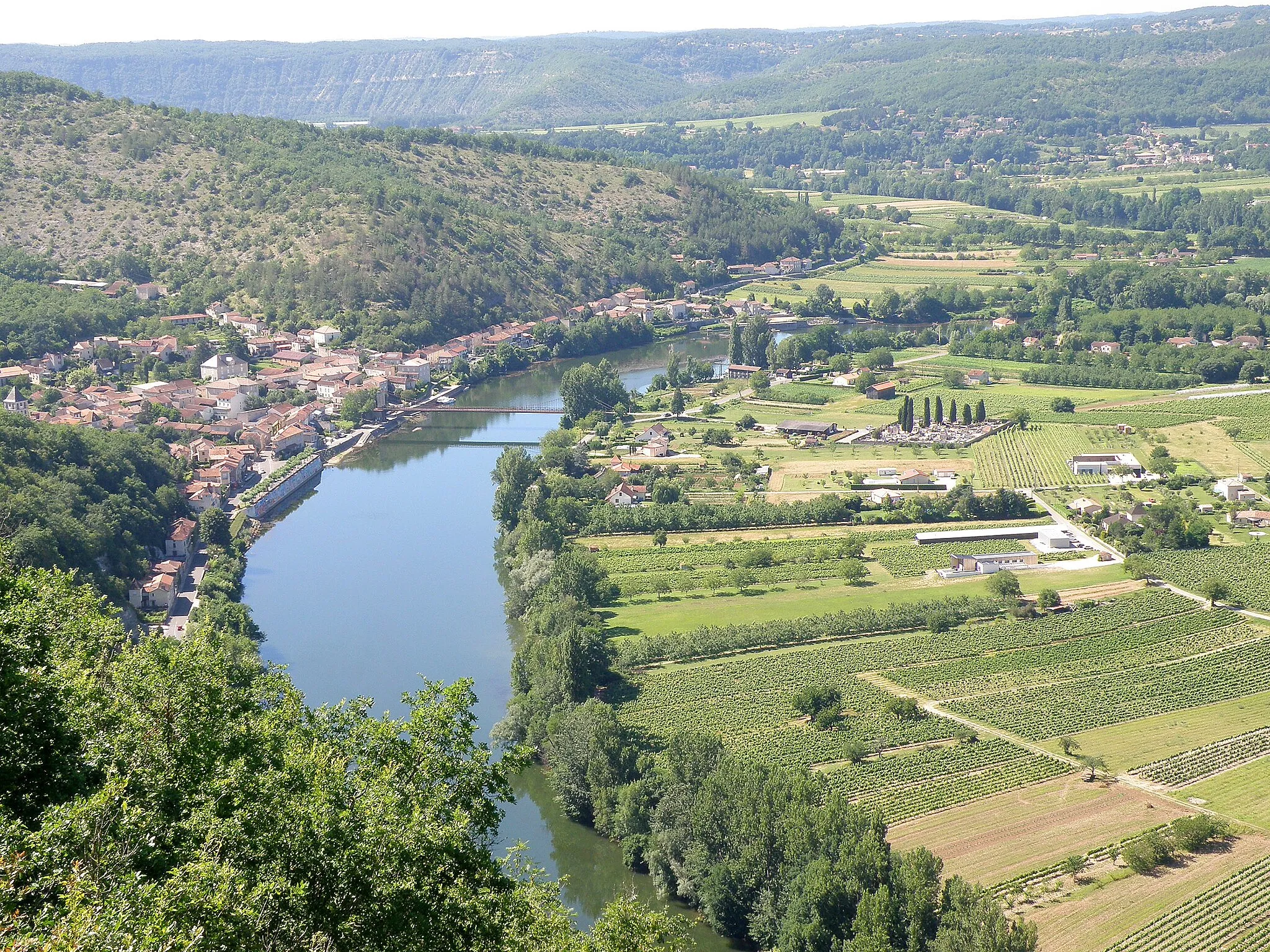 Photo showing: Douelle, commune du département du Lot, France (région Midi-Pyrénées). Vue générale du bourg, situé sur la rive gauche du Lot. Vue prise depuis la cévenne de Douelle, au sud-est du bourg. La plaine à droite, déterminée par une boucle du Lot, appartient également à la commune.