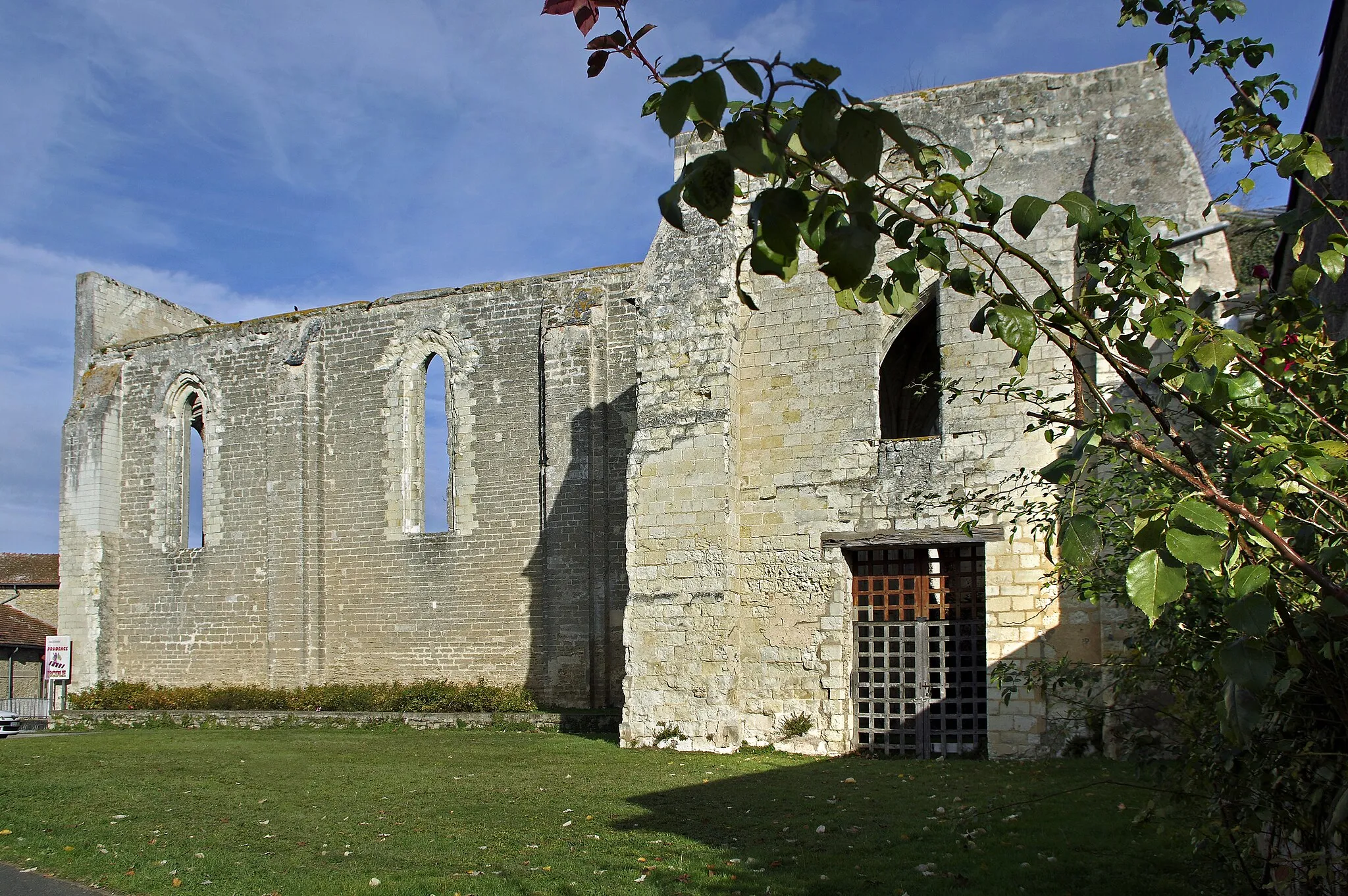 Photo showing: Doué-la-Fontaine (Maine-et-Loire)
Collégiale Saint-Denis.
Avant 1040, il existe sur le site une communauté monastique masculine.
L'église Saint Denis fut dédiée en 1040 et devint collégiale en 1063 avec la création par Gontier seigneur de Doué, d’un chapitre de quatre chanoines (d'abord 4 prébendes, puis 8, puis 6), richement doté. Le chapitre comprendra 4 chanoines de 1040 à 1063, puis 8 chanoines jusqu'en 1129, ensuite 6.
Ses revenus étaient tels que les moines de l’abbaye de Cunault n’hésitèrent pas à produire un faux document (le diplôme de Dagobert) attestant leurs droits sur les biens de la collégiale. Ce faux diplôme de Dagobert, daté de 631, a été forgé en réalité au XVIe siècle.
Une charte de 1063 confirme bien que la fondation remonte au XIe siècle : Gontier, un des seigneurs se partageant avec les prêtres les revenus des églises de Doué, a établi un collège de quatre chanoines, dont son fils. L'acte précise que  les chanoines remplacent les moines du "monastérium Sancti Dionisii". (Gontier, pourrait bien être le premier seigneur héréditaire de Doué. La ville, avant d'être seigneurie, avait des vicaires, vicarii de Doado castro, c'est-à dire des officiers non héréditaires chargés de la défendre et de la gouverner au nom des comtes d'Anjou. Un de ses officiers eut un fils, Gauthier, qui à la fin du XI siècle devint seigneur héréditaire de Doué).
Ensuite, les chanoines de Doué passeront sous la dépendance de la cathédrale d'Angers, jusqu'à ce que le pape Urbain II, en 1096, confie la nomination des prébendes à l'abbé de Tournus, déclenchant ainsi un conflit (À partir du XIIe siècle, on distingue les chanoines séculiers et les chanoines réguliers, les chanoines séculiers, qui vivent dans le monde, tirent leurs moyens de subsistance d'un bien appelé prébende). Le conflit sera résolu, en 1129, par un accord entre l'évêque d'Angers Ulger (Ulgerus) et l'abbé de Tournus : Les chanoines cédaient leur église à Tournus, s’engageaient à recevoir l’abbé, et promettaient de déposer un cens annuel sur l’autel du prieuré de Cunaud dépendant de l’abbaye de Tournus. En échange, l’évêque obtenait à perpétuité la présentation et la collation des prébendes dont le nombre, passé à 8, était ramené à 6.
Reconstruite au XIIe siècle, entre 1180 et 1200, la collégiale se situe à la transition du roman et du gothique et mélange pierres de tuffeau et pierres de falun.
Au XIII e siècle, le chapitre Saint-Denis participait à la nomination du comptable de l'hôpital, fondé en 1229 par la pieuse dame Eustache sur ses biens propres, avec le seigneur et les bourgeois de la ville.
La collégiale prospèra pendant plus de trois cents ans avant de subir les guerres du XIVe siècle, puis les guerres de religion au XVIe siècle.
En 1500, la cure de l'église paroissiale Saint-Pierre est unie par le pape à la collégiale.
Le chapitre disparaît en 1791.
Désaffectée en 1806, la collégiale est vendue à des particuliers en 1811, puiqs, elle passa de main en main amplifiant ainsi sa détérioration malgré son classement aux monuments historiques dès 1862. La commune la rachètera le 30 décembre 1889 et commencera à la consolider. Elle fut frappée par la foudre en 1898.
L'église est en forme de croix latine avec une grande nef et un choeur circulaire. A l’origine, l’édifice mesurait 51 m de long pour 33 m de large. Un clocher s'élevait autrefois à la croisée du transept.
L'architecture de style plantagenêt est un exemple de la transition romano-gothique de l'Anjou : les chapiteaux sont romans et une partie de la voûte plantagenêt.

Panneau explicatif devant l'édifice.
www.ville-douelafontaine.fr/user/documents/fichiers/vivre...
fr.wikipedia.org/wiki/%C3%89glise_Saint-Denis_de_Dou%C3%A...

Collégiales urbaines et collégiales castrales dans le diocèse d’Angers au Moyen Âge Jean-Michel MATZ - Maître de conférences en histoire médiévale - Université d’Angers : abpo.revues.org/1693?file=1