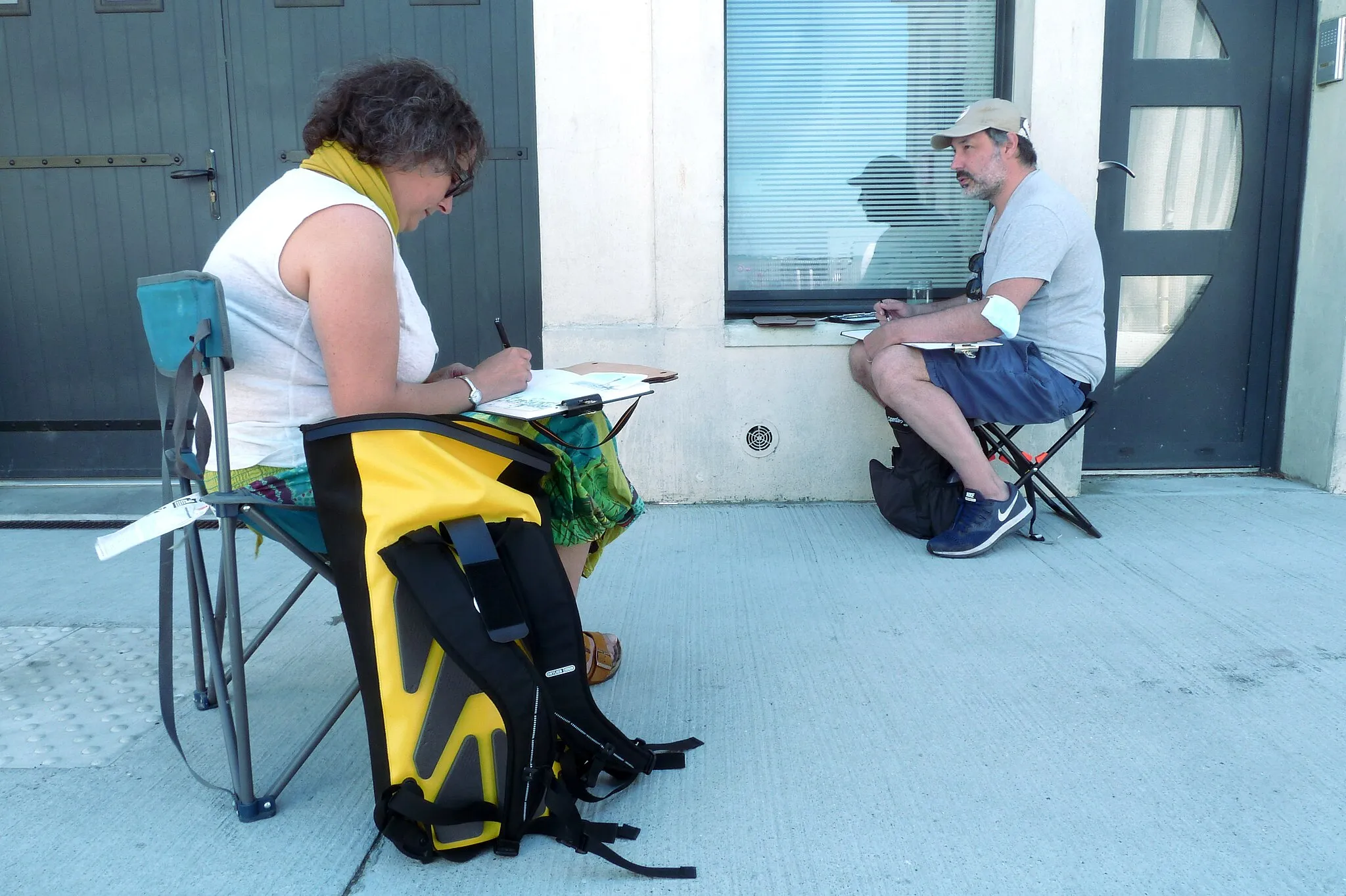 Photo showing: A woman and a man, “Urban Sketchers”, draw in a street in Paimbœuf (West of France).