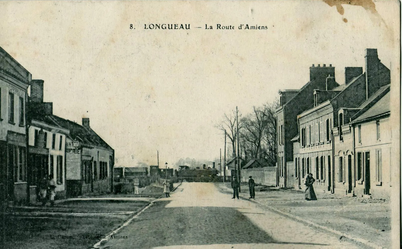 Photo showing: Carte postale ancienne éditée par Caron à Amiens, n°8 Longueau : La Route d'Amiens Vue du passage à niveau, avant l'édification du pont.