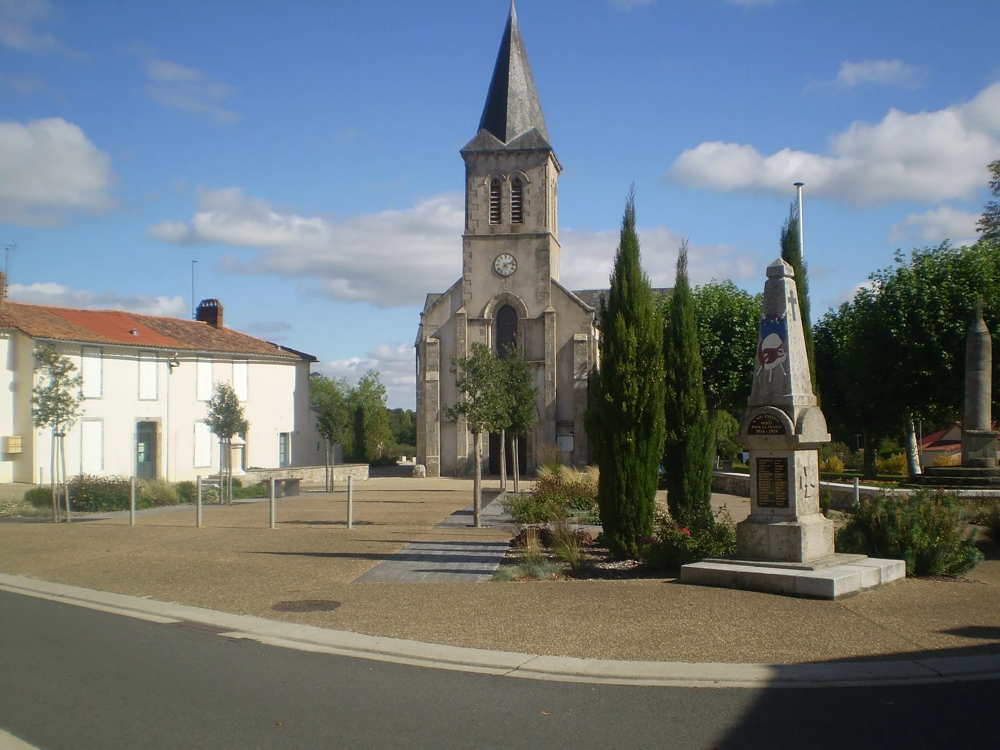 Photo showing: La place du Bailli Ayrault rassemble au cœur du bourg l'église St Pierre, l'ancien presbytère, le monument aux morts et la croix hosannière qui était autrefois au centre du cimetière aujourd'hui à l'extérieur du bourg.