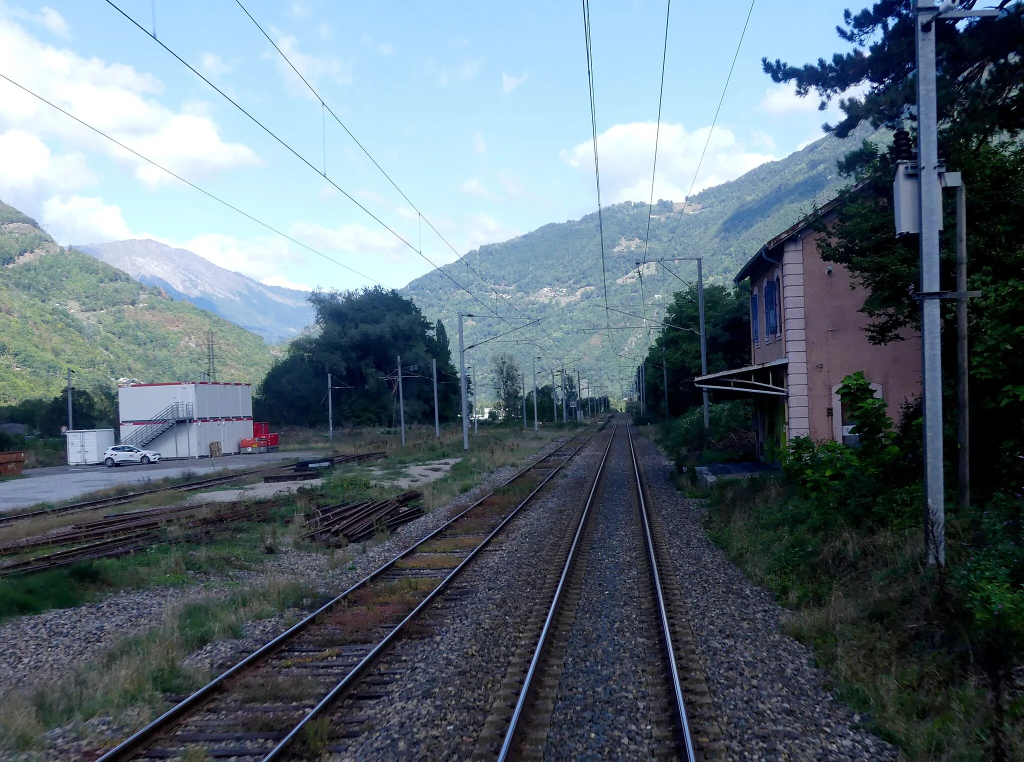 Photo showing: Sight, in a cloud shadow, of former La Bâthie railway station closed in the 1990s, towards Albertville, Savoie, France.