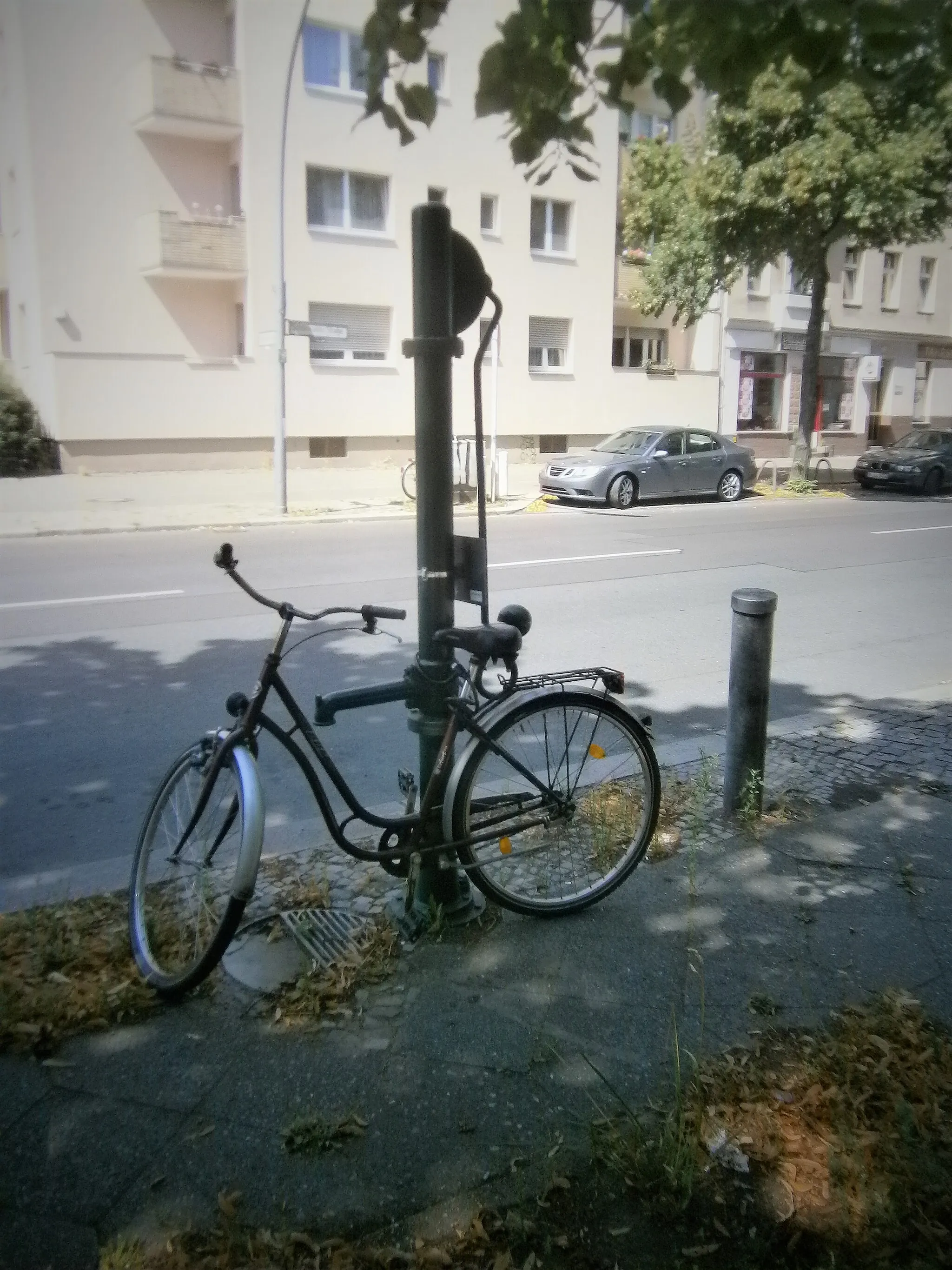 Photo showing: Bis in die 2010er Jahre war ein grünlackierter Schliephacke-Brunnen aus den 1960er Jahren an der östlichen Straßenseite gegenüber der Mündung der Marschallstraße aufgestellt. Ersetzt wurde er am gleichen Ort und mit gleicher Kennzeichnung durch einen FSH-Brunnen. Der Wasseraustritt ist an einer kurzen Hülse am Rohr verschraubt. Schwengel und Austritt stehn sich gegenüber. Der Wasserfluss ist erfolgreich. Neben dem Brunnenfuß liegt der Straßeneinlass zur Hälfte auf dem Kleinpflasterrand und halb zwische den Gehwegplatten, wobei der Streifen der Straßenbäume am der fahrbahnabgewandten Seite liegt. Der 10 Meter breite Bürgersteig darauf mit dem Brunnen liegt gegenüber der mündenden Marschallstraße. Die fünfgeschossige Wohnbebauung 43/43a/44/44a der Häuserzeile in Höhe des Brunnens in der Spandauer Neustadt entstand in den 1960er Jahren.[1] Die kriegsbeschädigten Einzelhäuser wurden dafür beräumt.