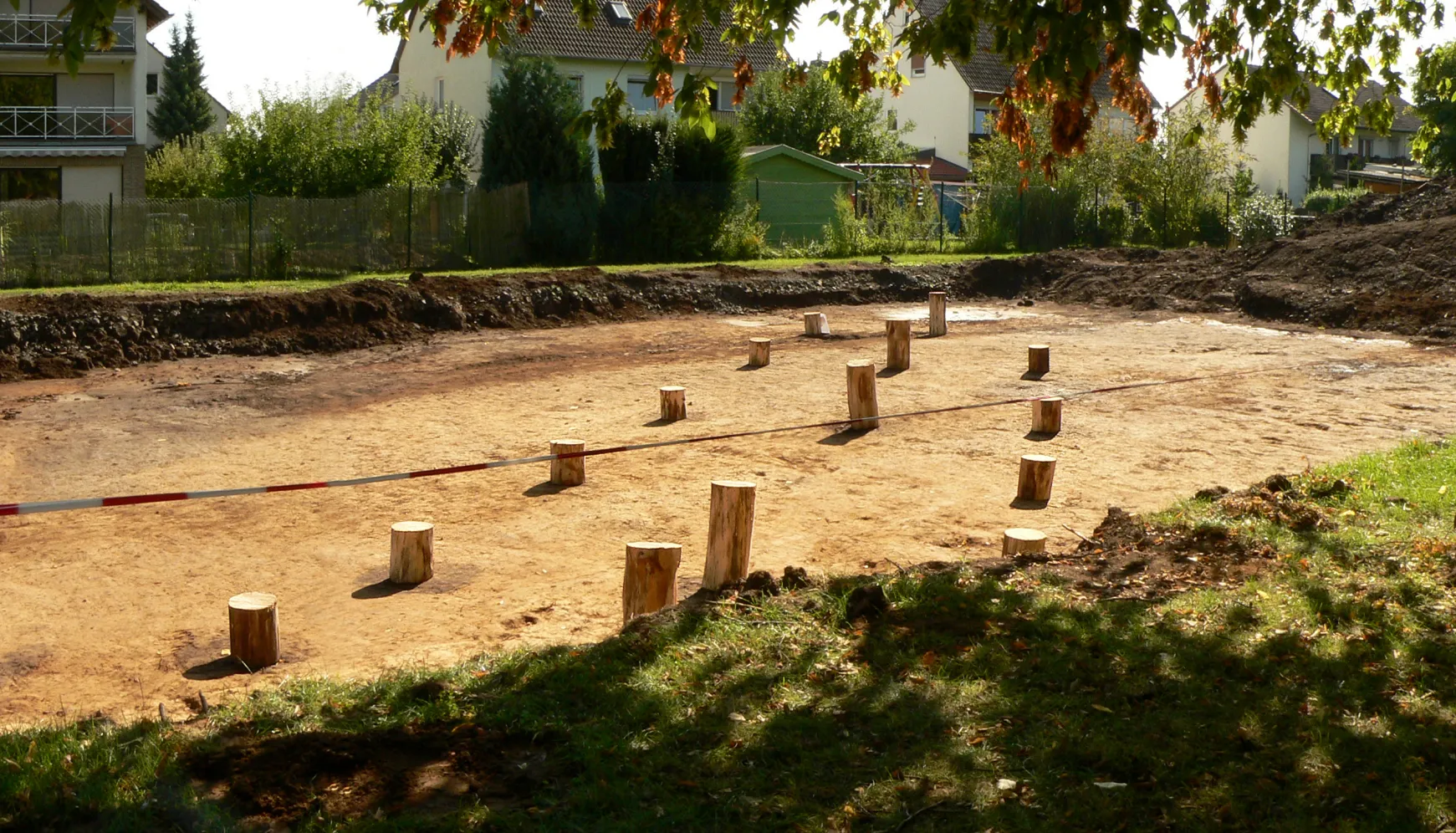 Photo showing: Grabungsfläche 2016 der Siedlung Rosdorf Mühlengrund mit rekonstruiertem Hausgrundriss anhand von Pfostenlöchern, zur Kenntlichkeit mit Baumstämmen markiert