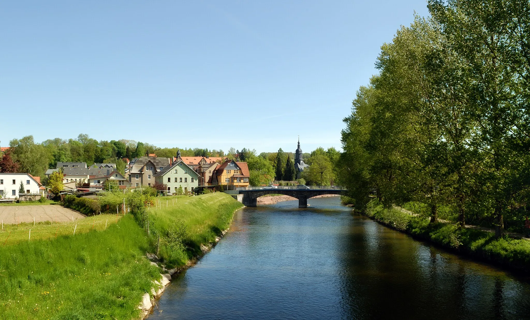 Photo showing: This image shows the river Flöha in the town Flöha, Germany. In the background there is a bridge with the Augustusburg street and the George church.