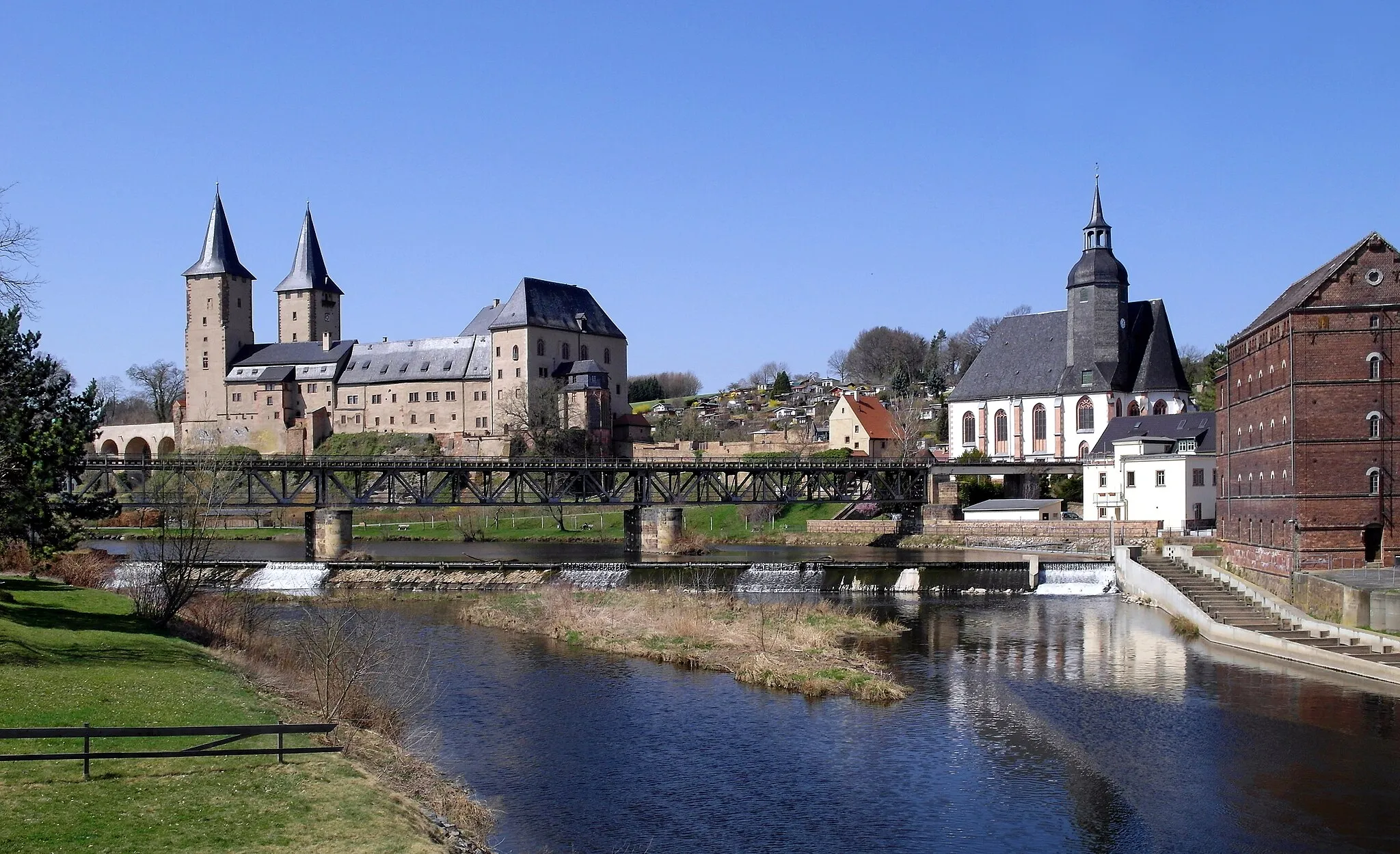 Photo showing: 10.04.2018   09306  Rochlitz: Schloß (GMP: 51.045068,12.791399). Die erste Burg wurde hier im 10. Jahrhundert von König Heinrich I. gegründet. Das heutige Schoß geht auf Markgraf Wilhelm I. von Meißen Ende des 
14. Jahrhunderts zurück. Seit dem 18. Jahrhundert war das Schloß nur noch Behördensitz. Die Gerichtsnutzung endete erst 1990. In Bildmitte die Eisenbahnbrücke (GMP: 51.044717,12.793452), ausgeführt als Stahl-Fachwerkträgerbrücke. Die Bahnstrecke ist stillgelegt. Rechts die Petrikirche (GMP: 51.045234,12.792433) und rechts davor die Schloßmühle (GMP: 51.045043,12.794721). Sicht von Südosten vom Ufer der Zwickauer Mulde.                                                                                                                                                                                                                                                                     [SAM5246.JPG]20180410505DR.JPG(c)Blobelt