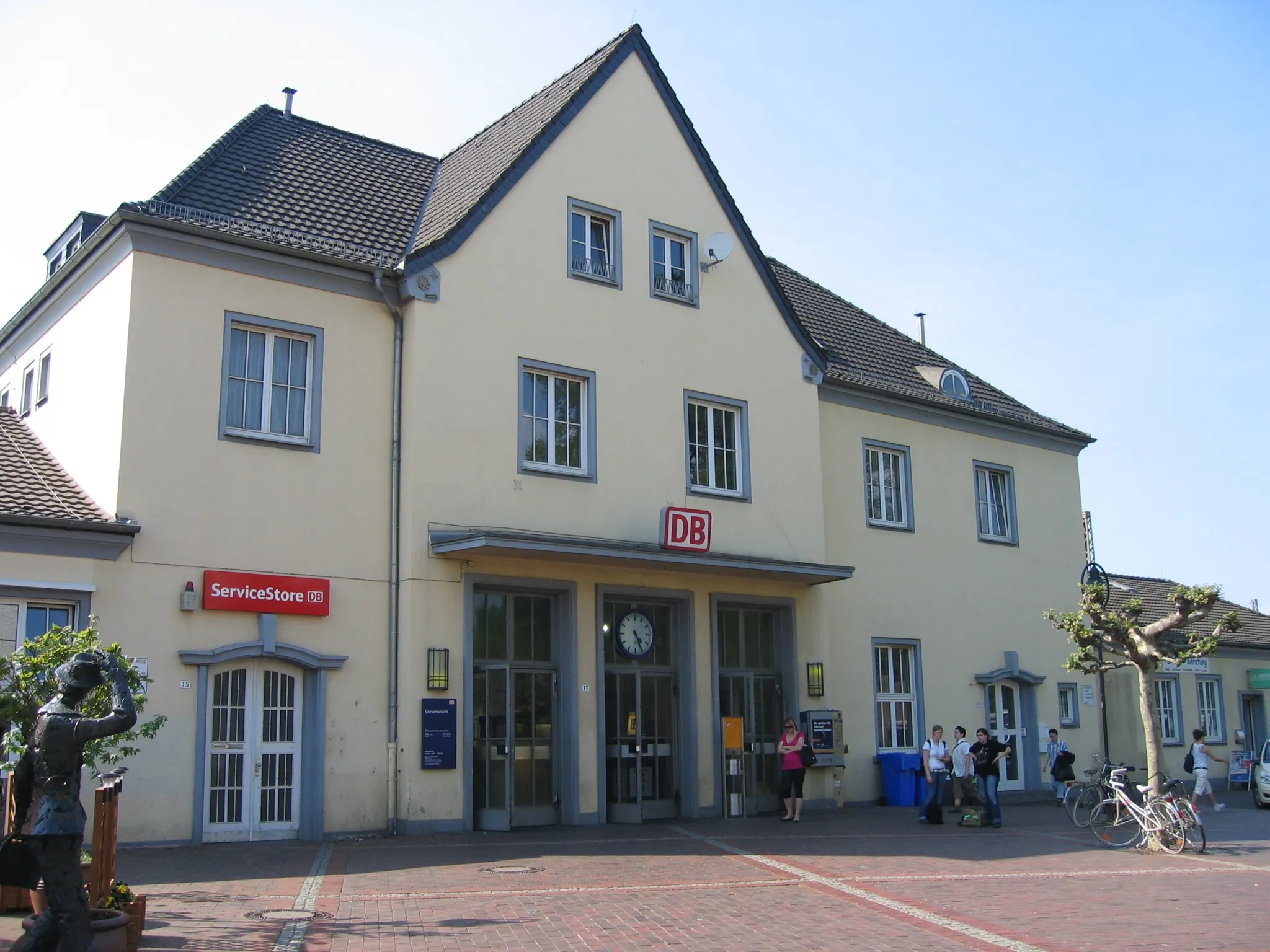 Photo showing: Bahnhof in Grevenbroich (Zugang Bahnhofsvorplatz), links am Rand ist noch eine Skulptur zu sehen, die im Volksmund als "Der letzte Beamte verlässt Grevenbroich" betitelt wird.