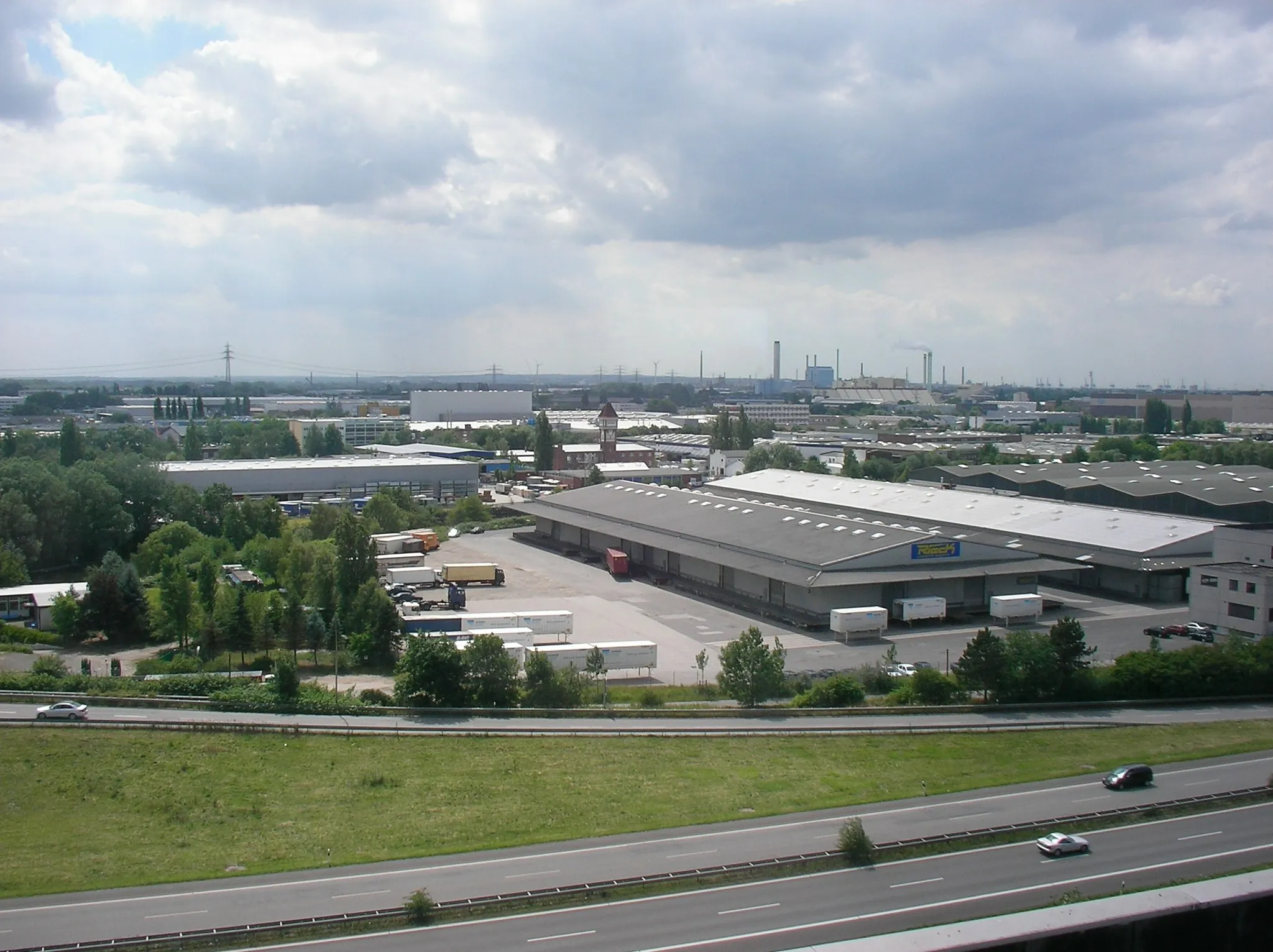 Photo showing: Hamburger Stadtteil Billbrook: Ein riesiges, zusammenhängendes Industrie- und Gewerbegebiet, das eine Ausdehnung von etwa drei mal drei Kilometern aufweist. Das Foto zeigt die Nord-Süd-Ausdehnung von der B5 im Norden (Vordergrund) bis zum Heizkraftwerk Tiefstack im Süden (größeres Gebäude am Horizont zwischen den Schornsteinen). Aufnahmeort ist das 9. Obergeschoss des Panorama Inn-Komplexes an der Billstedter Hauptstraße/Moorfleeter Straße.