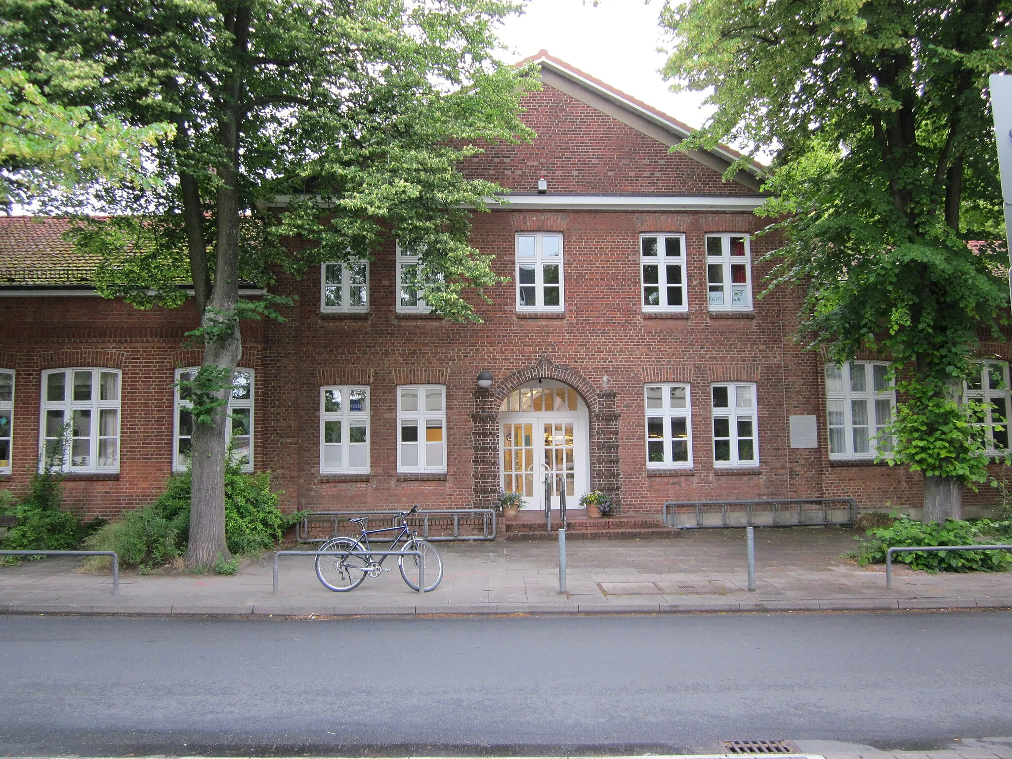 Photo showing: Die ehemalige Volksschule der früher selbständigen Gemeinde Sasel in der Kunaustraße entstand im Kern 1893, nachdem die alte Schulkate abgebrannt war. Zwischen 1922 und 1938 wurde die Schule mehrfach erweitert und bot ab 1939 auch den Erwerb der Mittleren Reife an. Nach dem Umzug der Schule in neue Gebäude 1980 war von 1987 bis 2007 die örtliche Öffentliche Bücherhalle im Gebäude untergebracht. Seit 2009 werden dort Menschen mit Behinderung in einer Tagesstätte betreut. This is a photograph of an architectural monument. It is on the list of cultural monuments of Hamburg, no. 1619.