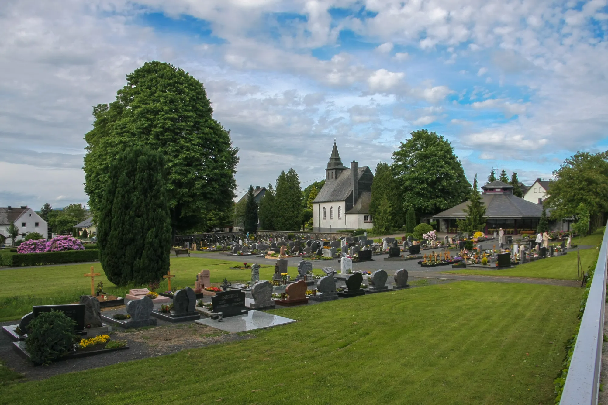 Photo showing: Friedhof der Gemeinde Höhn im Westerwald. Im Hintergrund die evangelische Kirche, rechts daneben die Friedhofshalle