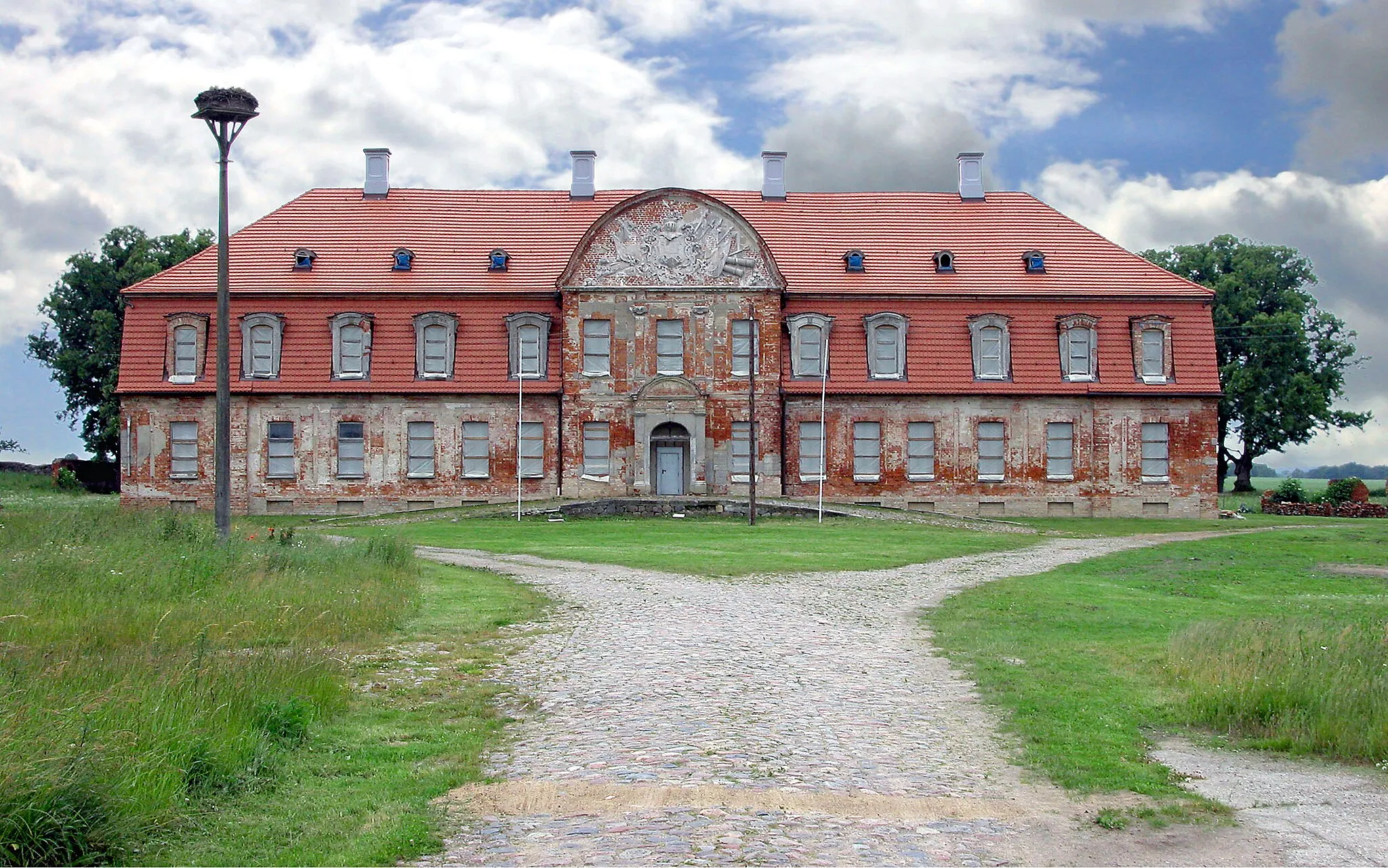 Photo showing: 26.06.2004   17019   Gützkow (Röckwitz), Dorfstraße (GMP: 53.725074,13.106744): Barockes Schloß als Herrenhaus des einstigen Ritterguts. Das symmetrische Gebäudeensemble aus repräsentativem Herrenhaus und den flankierenden Kavaliershäusern bildet einen weitläufigen Ehrenhof. Das Gutshaus wurde bis 1777 im Barockstil durch Adam von Blücher errichtet. Über dem Portal ist das Wappen der Familie von Blücher zu sehen. Im Zuge der Bodenreform wurde 1945 der letzte Besitzer Siegfried von Sydow enteignet. Im Haus wurden Wohnungen eingerichtet. Ab 1985 stand das Gebäude leer. 1998 erwarb Helmuth Freiherr von Maltzahn das Anwesen und begann mit dem Wiederaufbau. Hofseite.                                                                                                                                                                                                                                                                                                              [DSCN4221.JPG]20040625140DR.JPG(c)Blobelt