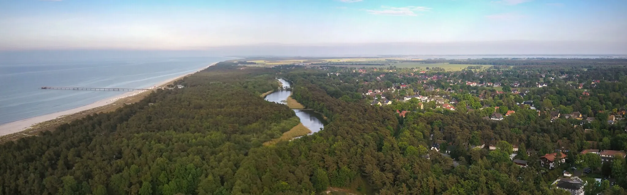 Photo showing: Prerow ist ein Seebad auf der Halbinsel Darß in Mecklenburg-Vorpommern. Links ragt die Seebrücke in die Ostsee, in der Mitte ist ein Ausläufer des Prerower Stroms zu sehen, der die Ortschaft vom Meer trennt. Rechts im Hintergrund das Boddenmeer.