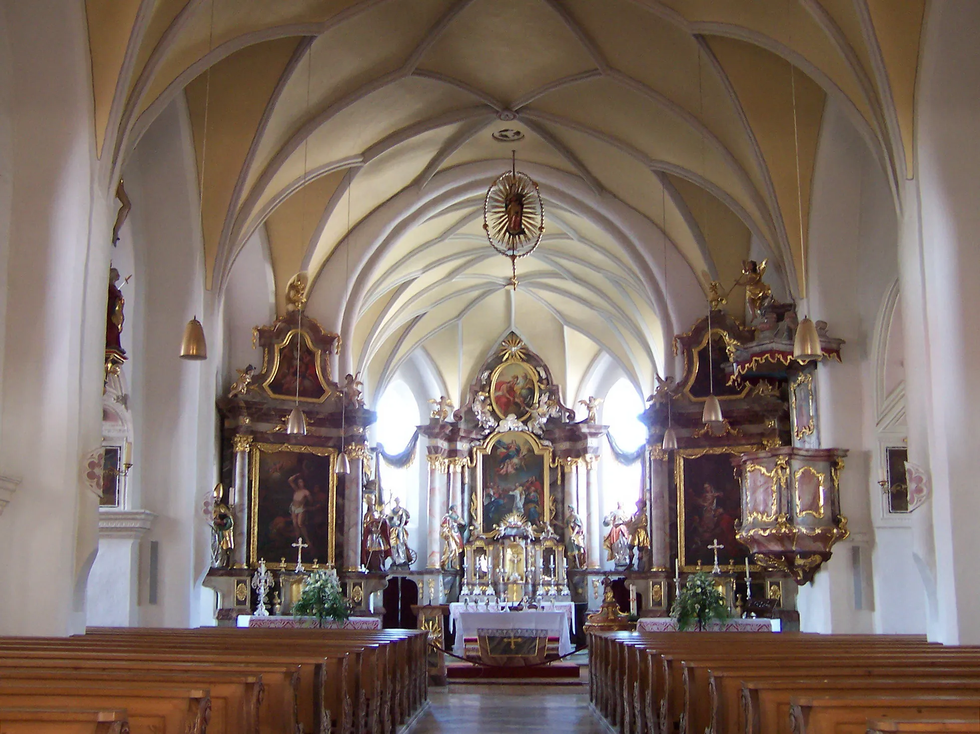 Photo showing: Essenbach, Rathausplatz 13. Katholische Kirche Mariä Himmelfahrt. Saalbau mit später angefügten Seitenschiffen, heute Staffelhalle, spätgotischer Bau um 1470, durch Seitenschiffe um 1670 und nochmals 1713 erweitert, im Kern romanischer Turm, spätgotisch erhöht, zunächst freistehend, 1713 in das südliche Seitenschiff integriert, Chor gegliedert durch Dreieckslisenen und Dachfries, mit Putzgliederung. Hauptschiff mit Netzgewölbe und drei Altären.