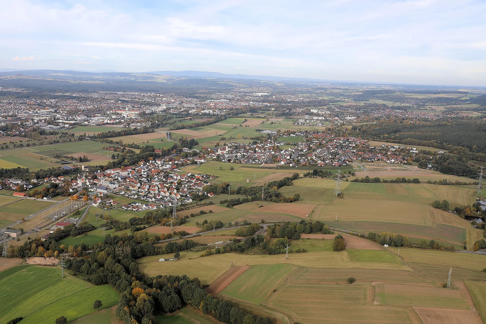 Photo showing: Schirmitz (Bildmitte), im Hintergrund die Stadt Weiden; Schirmitz, Landkreis Neustadt an der Waldnaab, Oberpfalz, Bayern