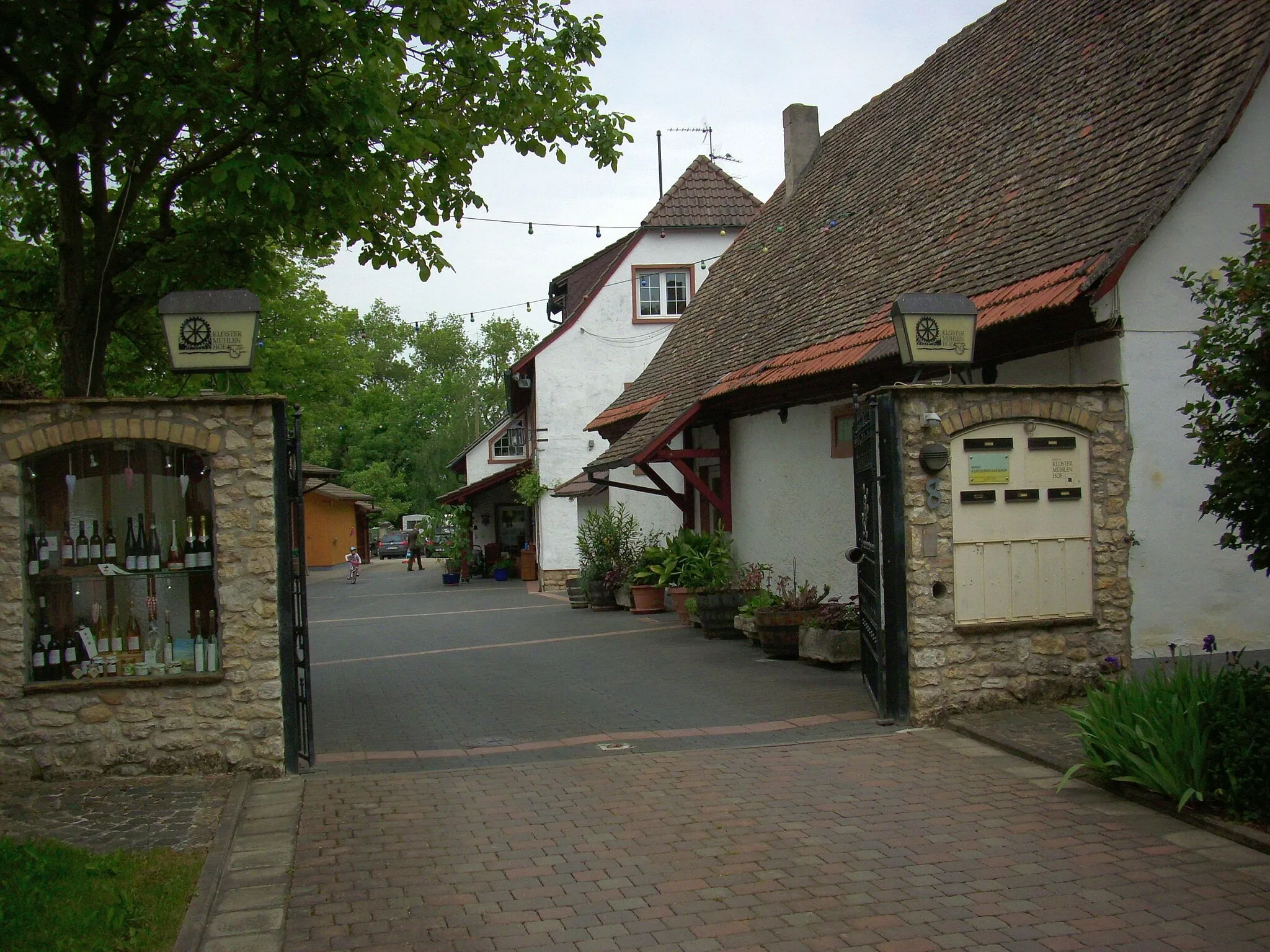 Photo showing: Ehemaliger Wirtschaftshof des Klosters Eberbach; zweigeschossiges barockes Hauptgebäude (Nr. 28/30) mit Krüppelwalmdach und halbrundem Kapellenanbau, 1722, nach Kriegsschäden 1953–58 wiederaufgebaut, Torbogen bezeichnet 1813; ehemaliges Abtshaus (Nr. 5a), stark erneuerter Walmdachbau, teilweise Fachwerk, im Kern aus dem 18. Jahrhundert; Mühle (Nr. 8), im Kern aus dem 18. Jahrhundert, mit Fachwerkobergeschoss; zwei barocke Doppelscheunen (Nr. 16/18, 20/22): Nr. 16/18 ehemalige Zehntscheune, langgestreckter Krüppelwalmdachbau, 18. Jahrhundert