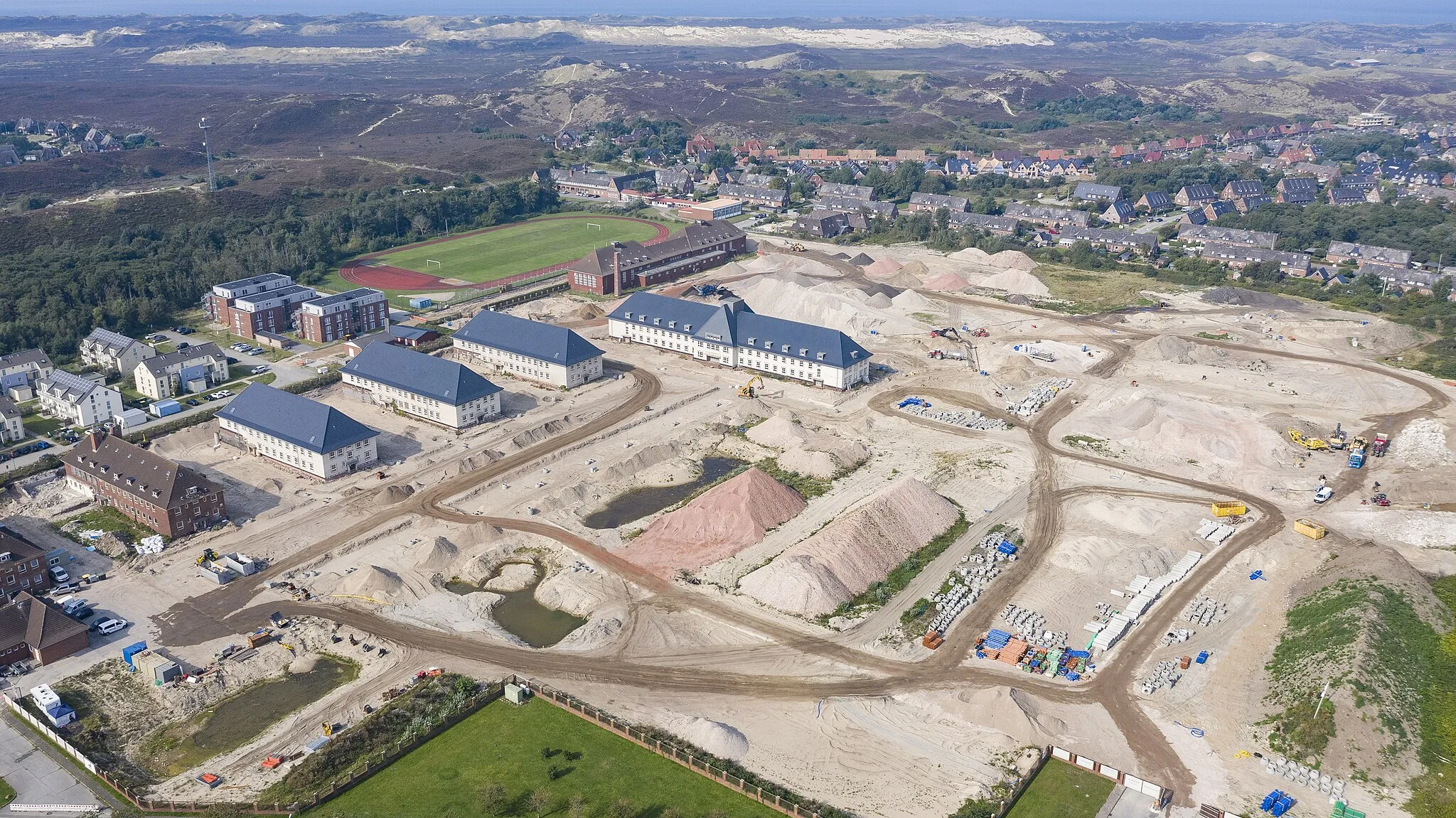 Photo showing: Aerial view of List, Sylt, Schleswig-Holstein, Germany. The area where some heavy construction work can be observed is the former site of the German navy's Supply School (MVS), that was seated here from 1956 until 2006. While some of the buildings still appear to be in their original state, those to the west have already undergone conversion. The buildings on the northern end of the former military site have apparently been demolished.