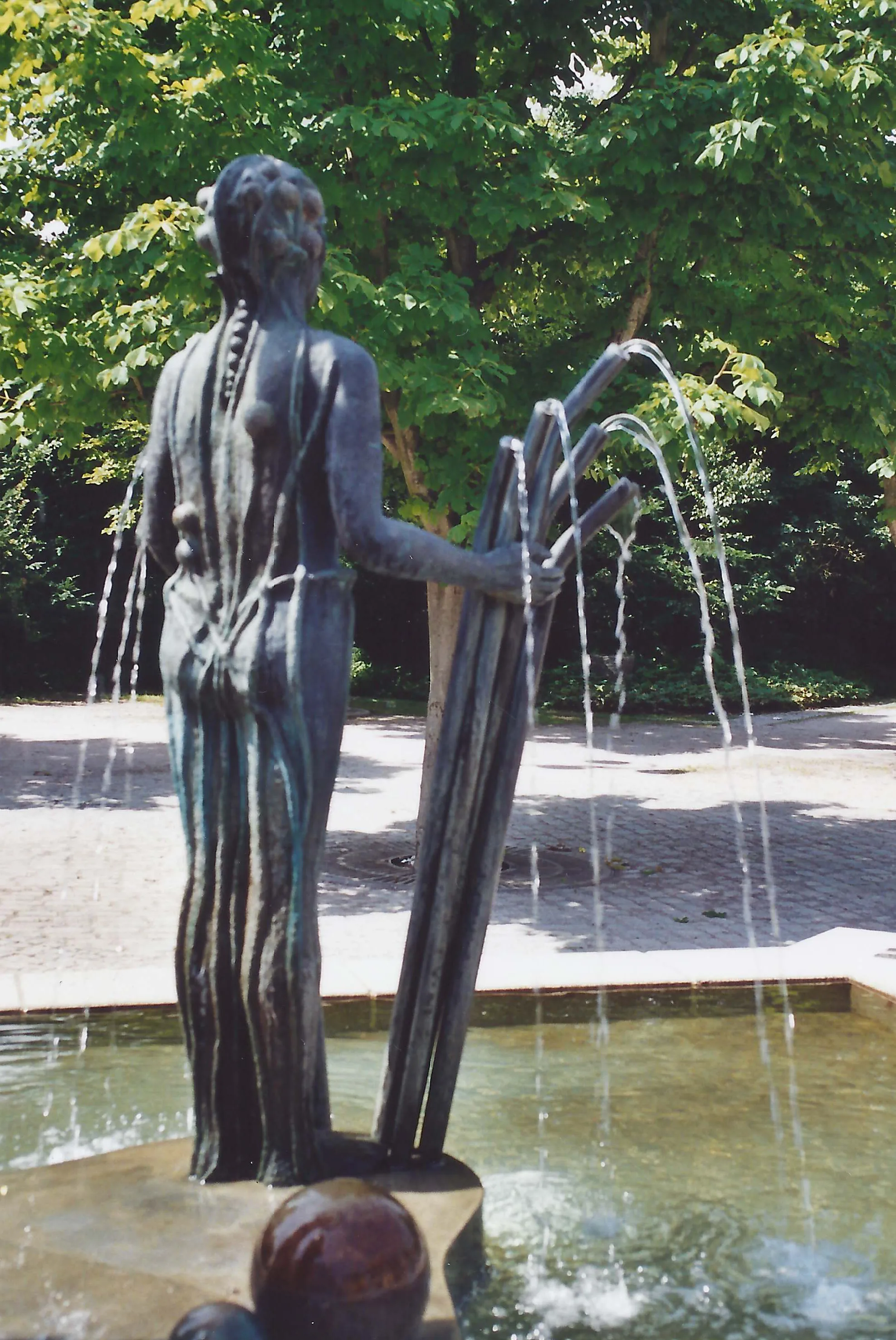 Photo showing: Jahreszeitenbrunnen (Röhrenfrau von hinten) von de:Ursula Stock, Bronze, Höhe 450 cm, 1991, Talheim, Rathausplatz 18.