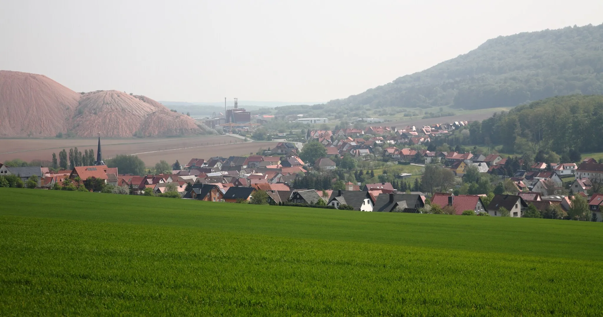 Photo showing: Die Ortschaft Holungen und der Kalischacht Bischofferode
(links im Hintergrund die Kali-Abraumhalde).